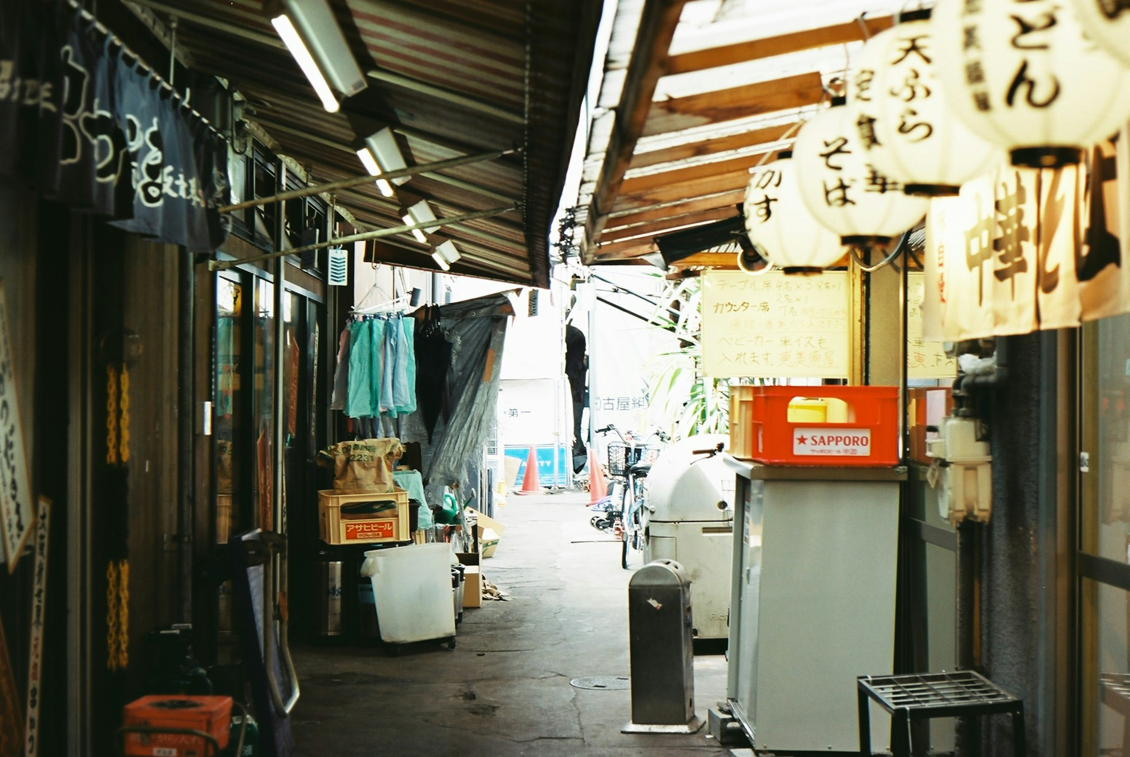 狭い日本の路地に並ぶ店舗と提灯