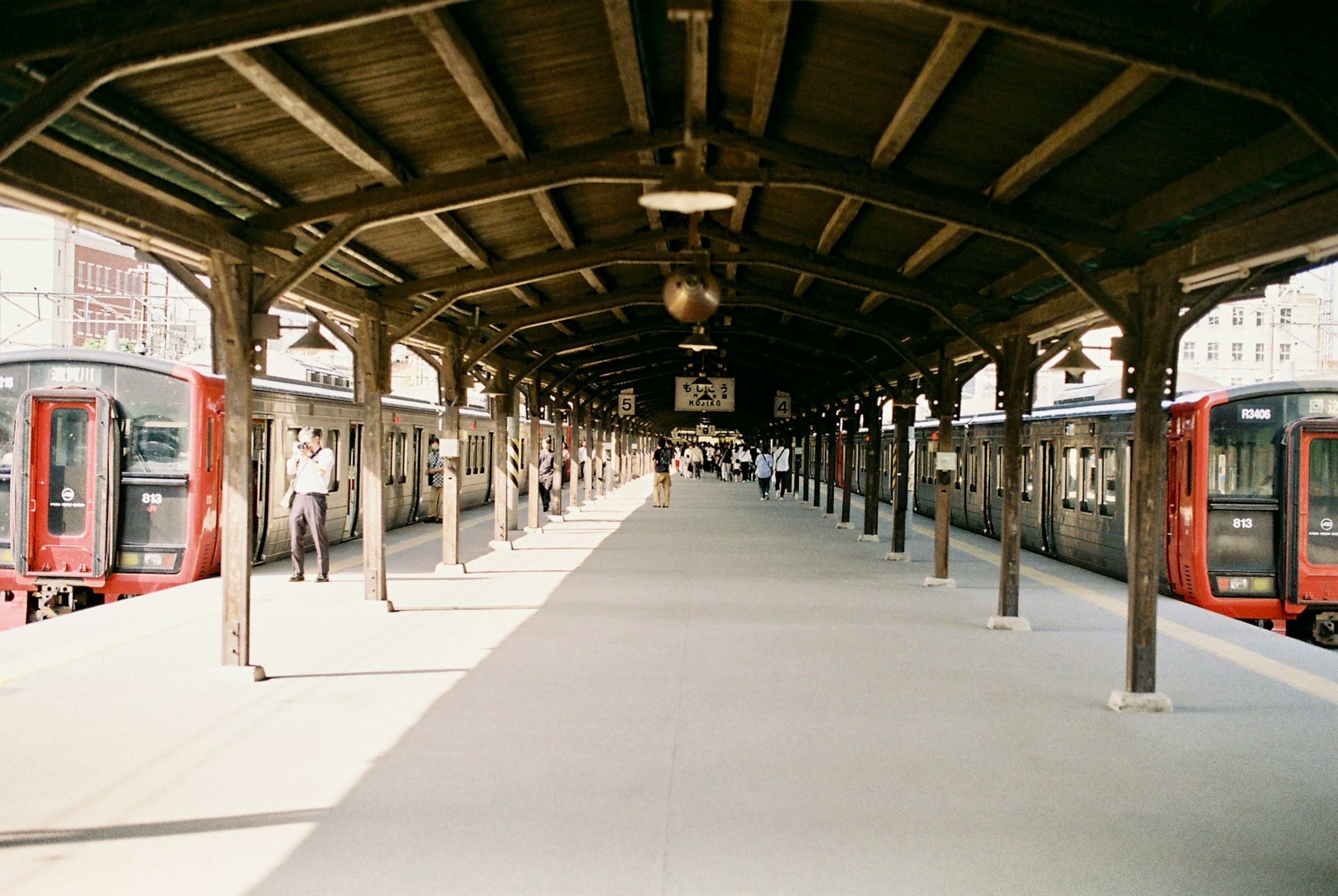 赤い電車と木製の屋根のある駅のプラットフォーム