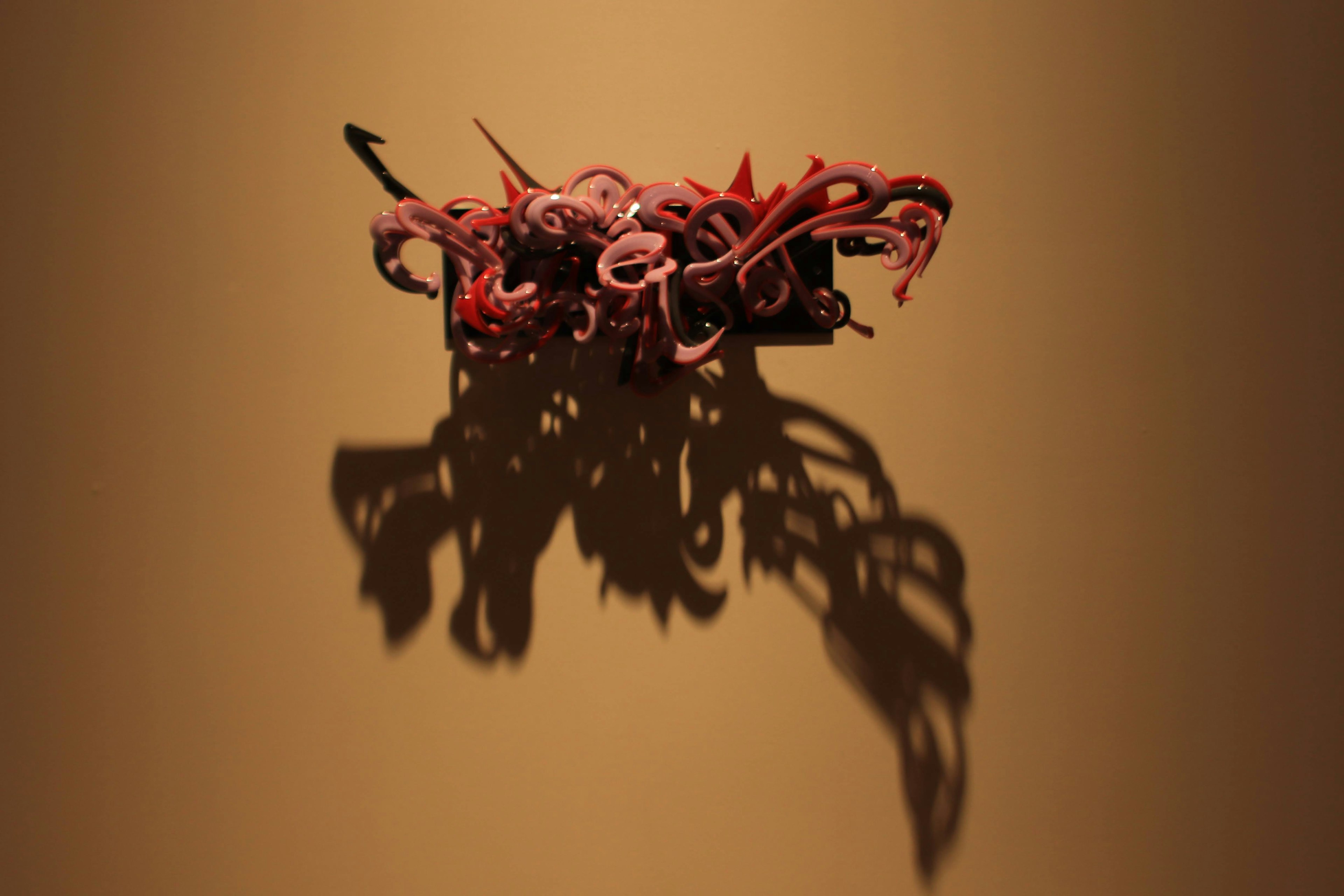 Art piece with red tentacles casting shadows on a wall