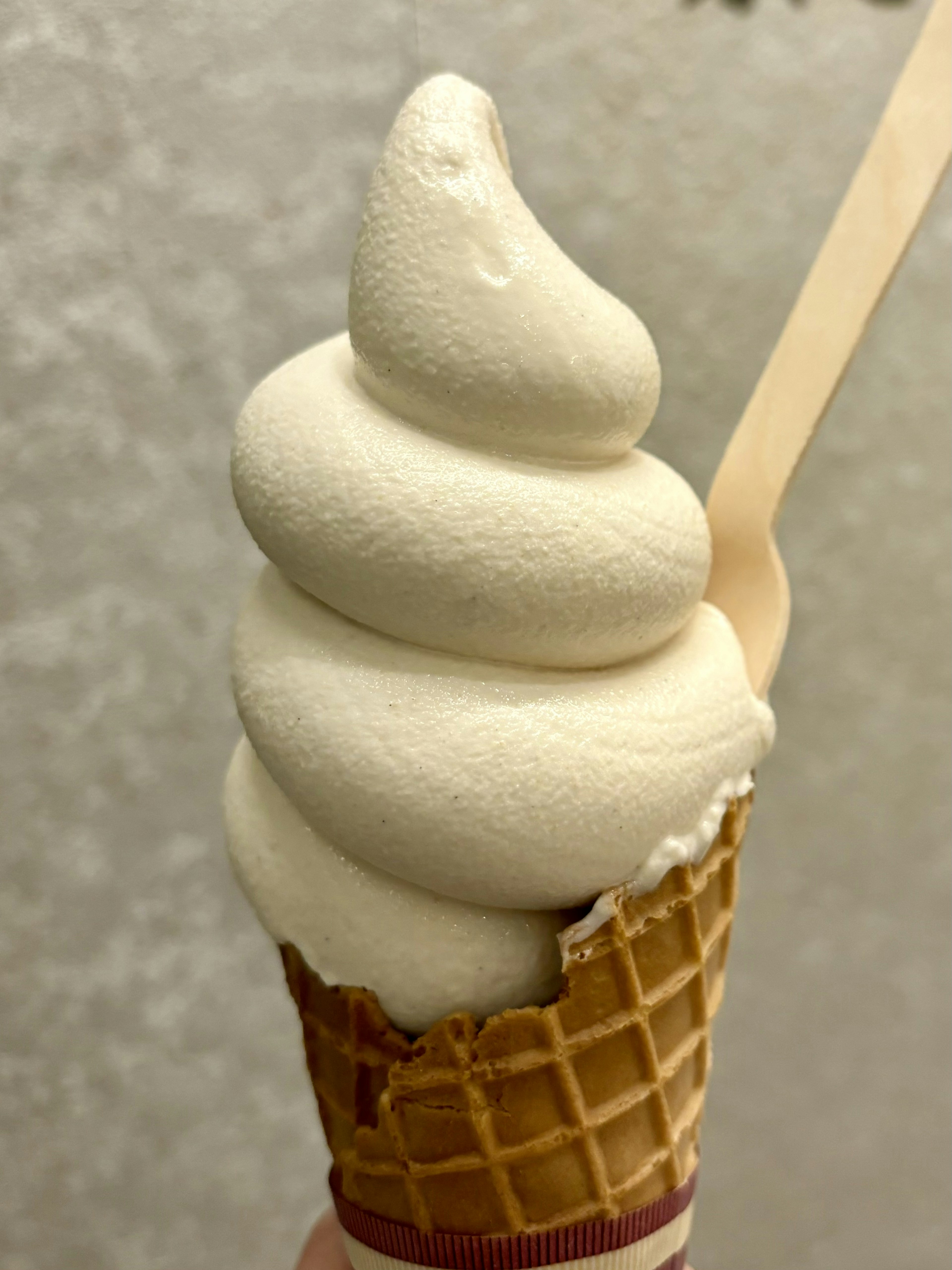 Soft serve ice cream in a waffle cone with a wooden spoon