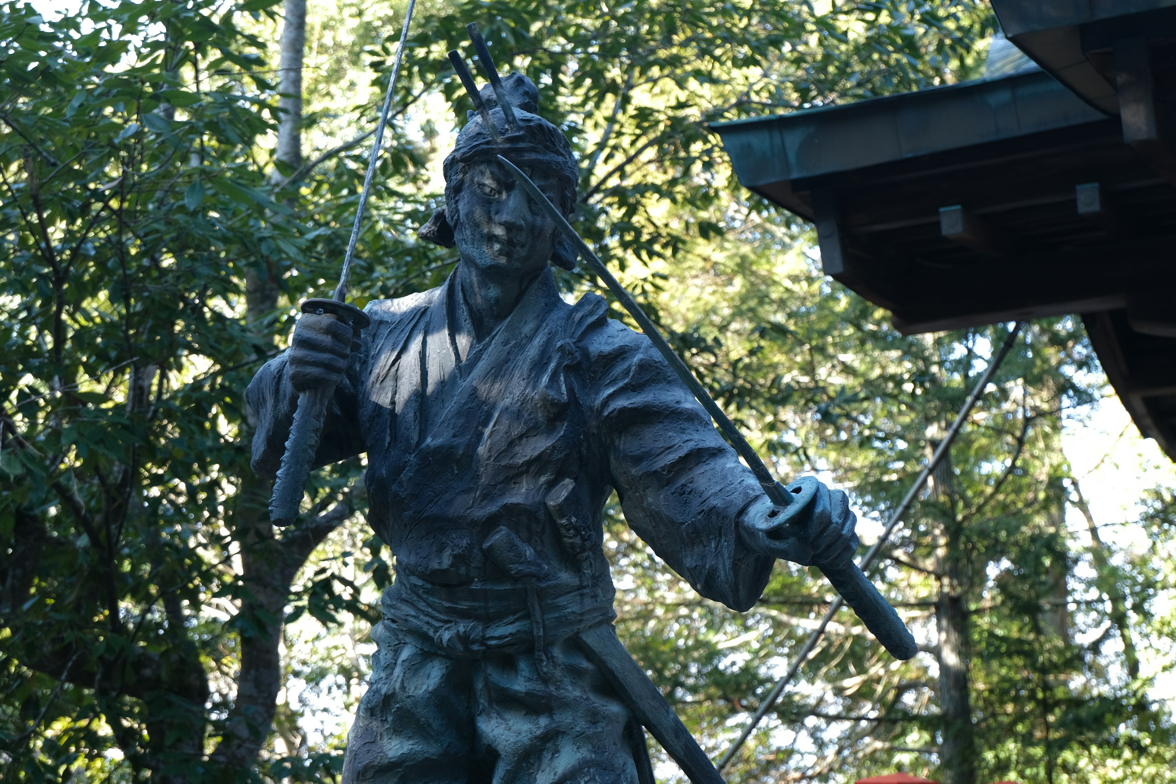 Une statue de samouraï tenant une épée dans un cadre naturel