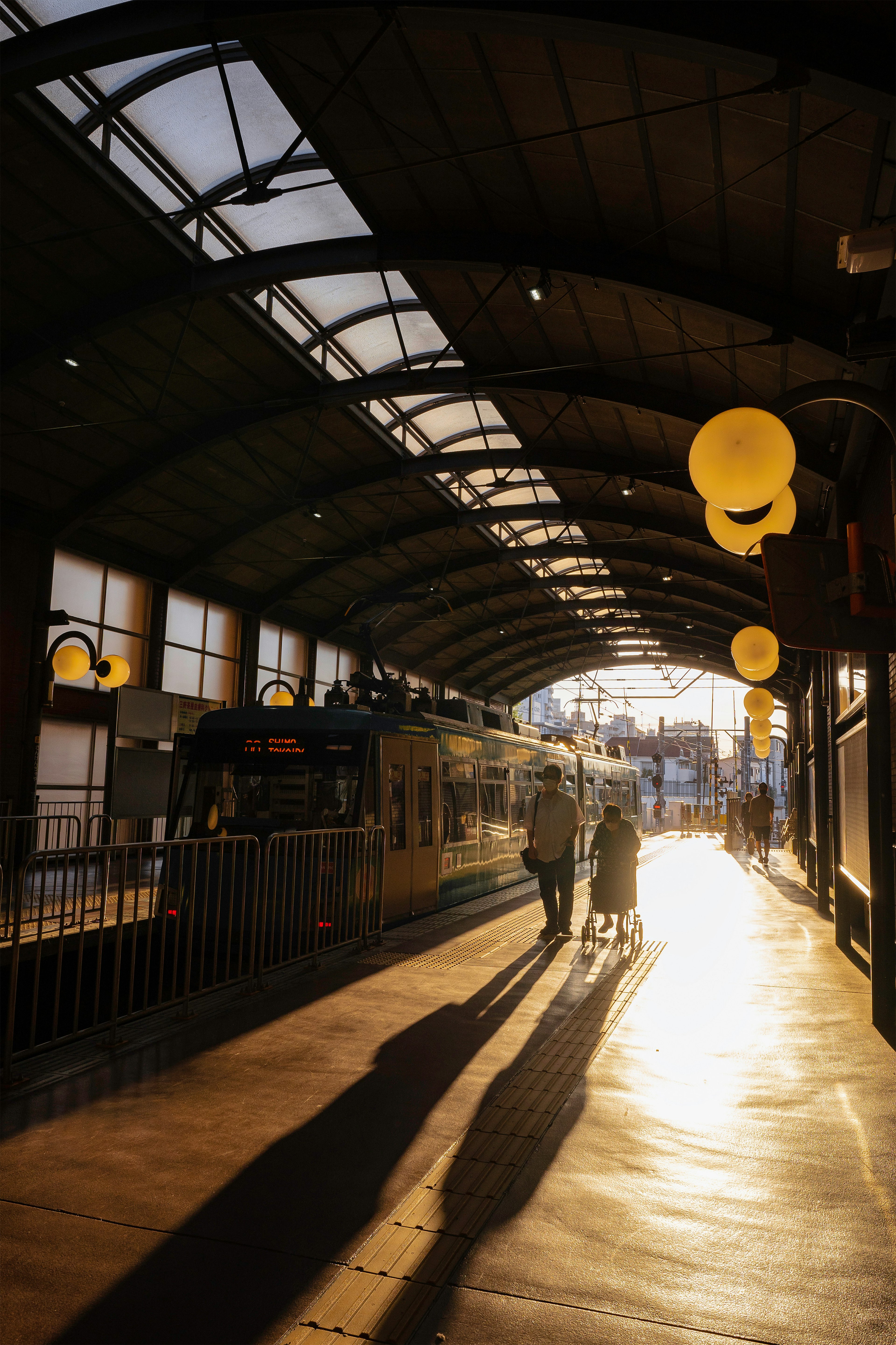 Silhouettes of two people walking on a sunlit train platform