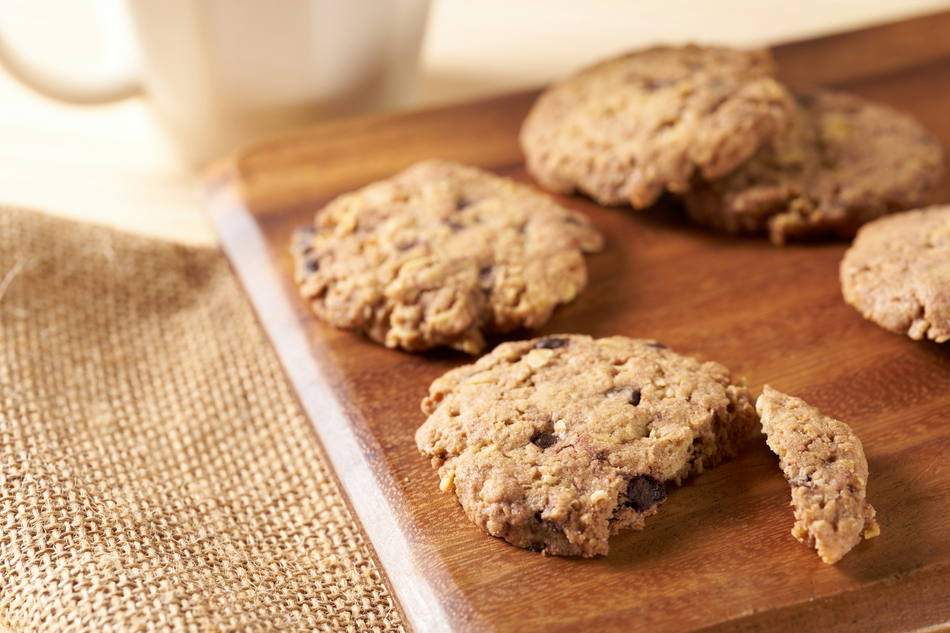 Chocolate chip cookies on a wooden board with a coffee cup