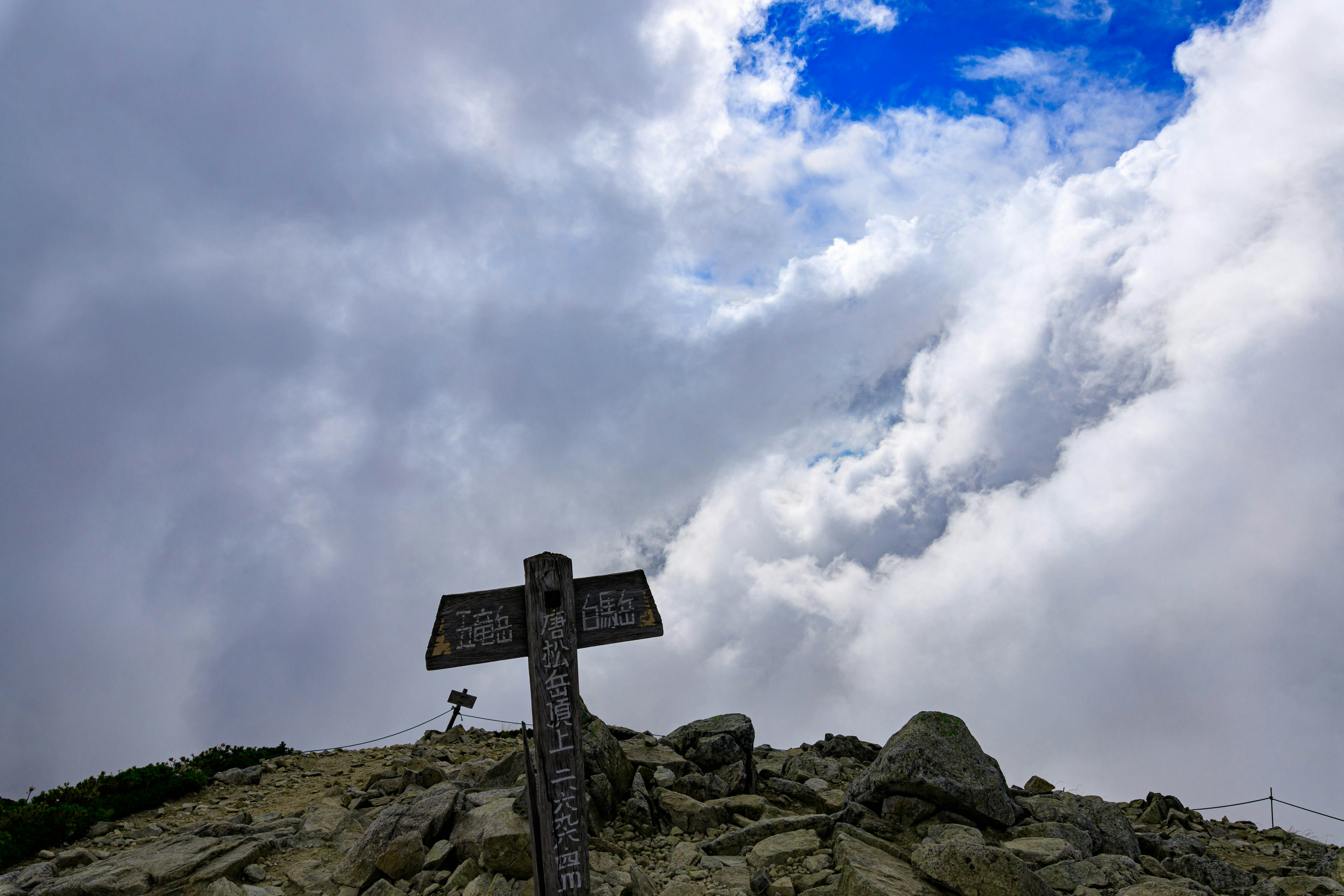 Segnale sulla cima della montagna con cielo nuvoloso