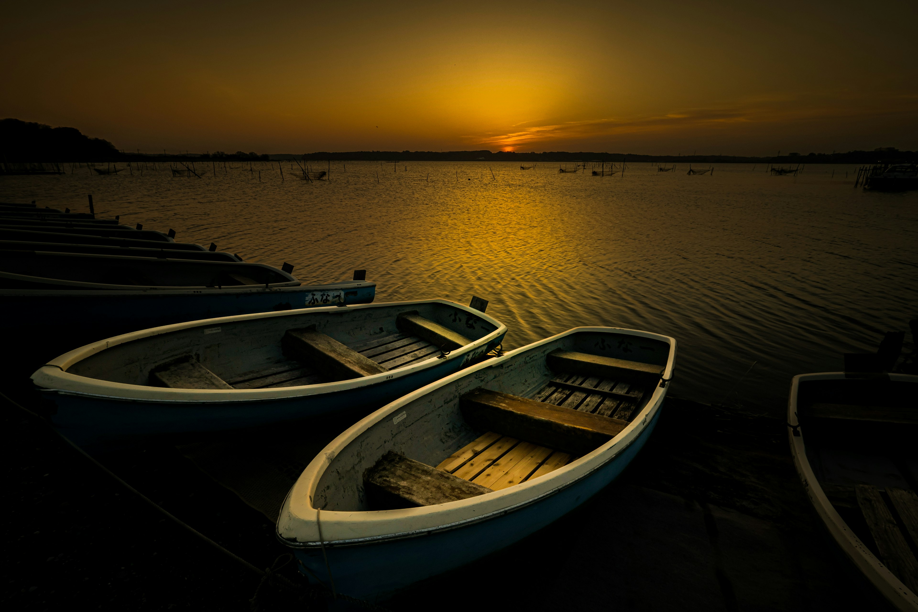 Danau tenang dengan perahu di latar belakang matahari terbenam