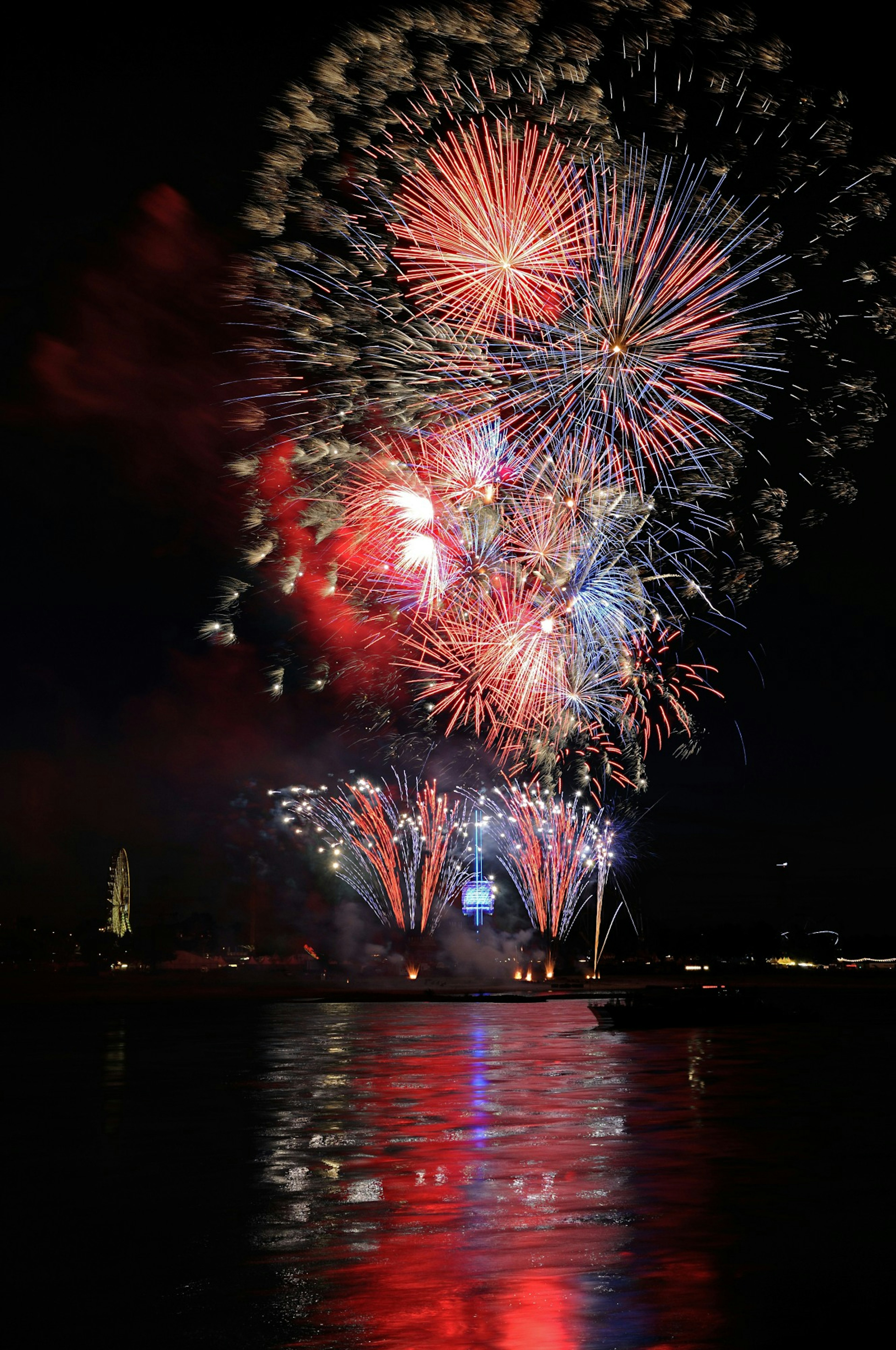 Fuegos artificiales coloridos iluminando el cielo nocturno con reflejos en el agua