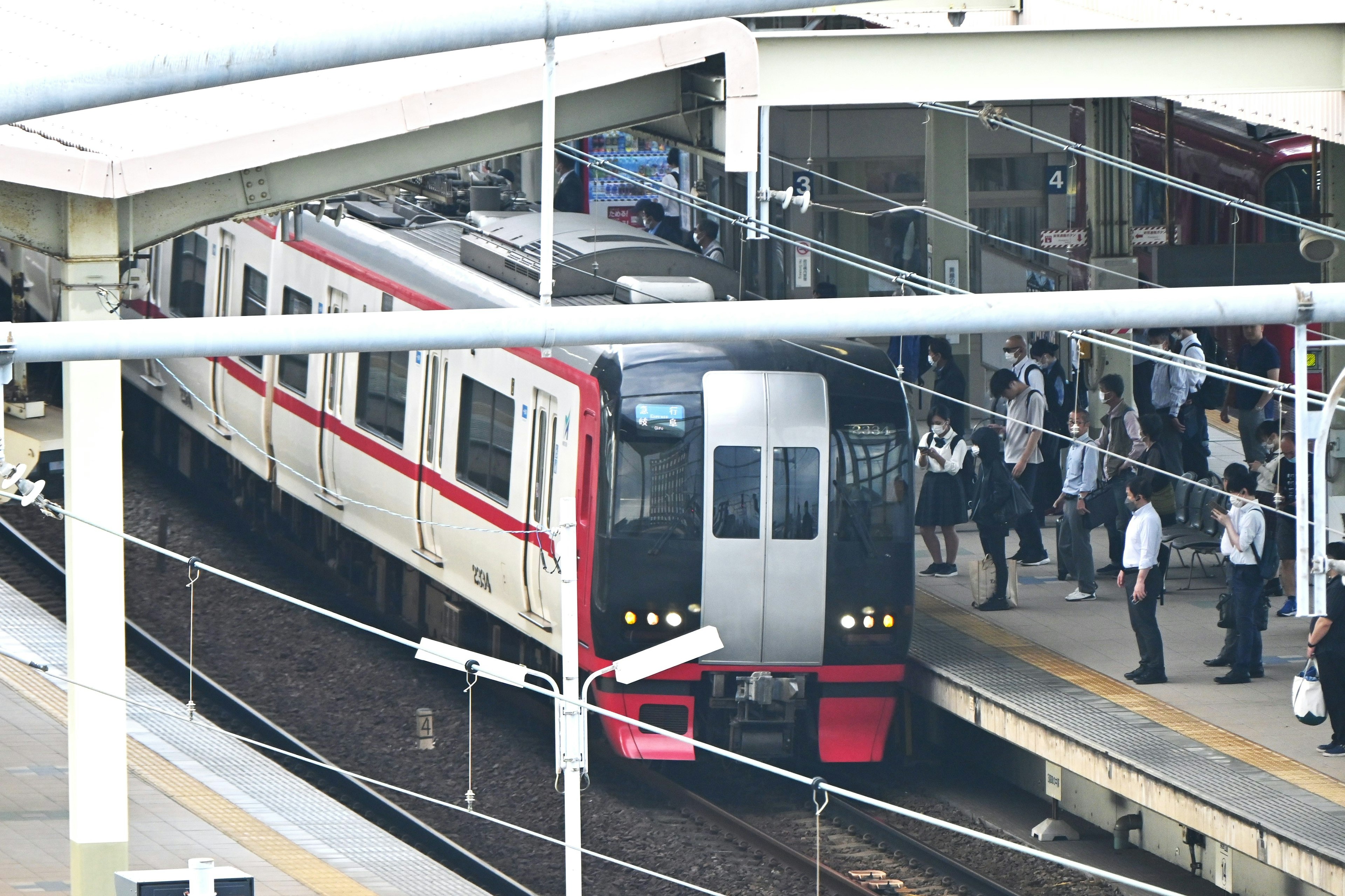 Passengers disembarking at a station with a red-lined train