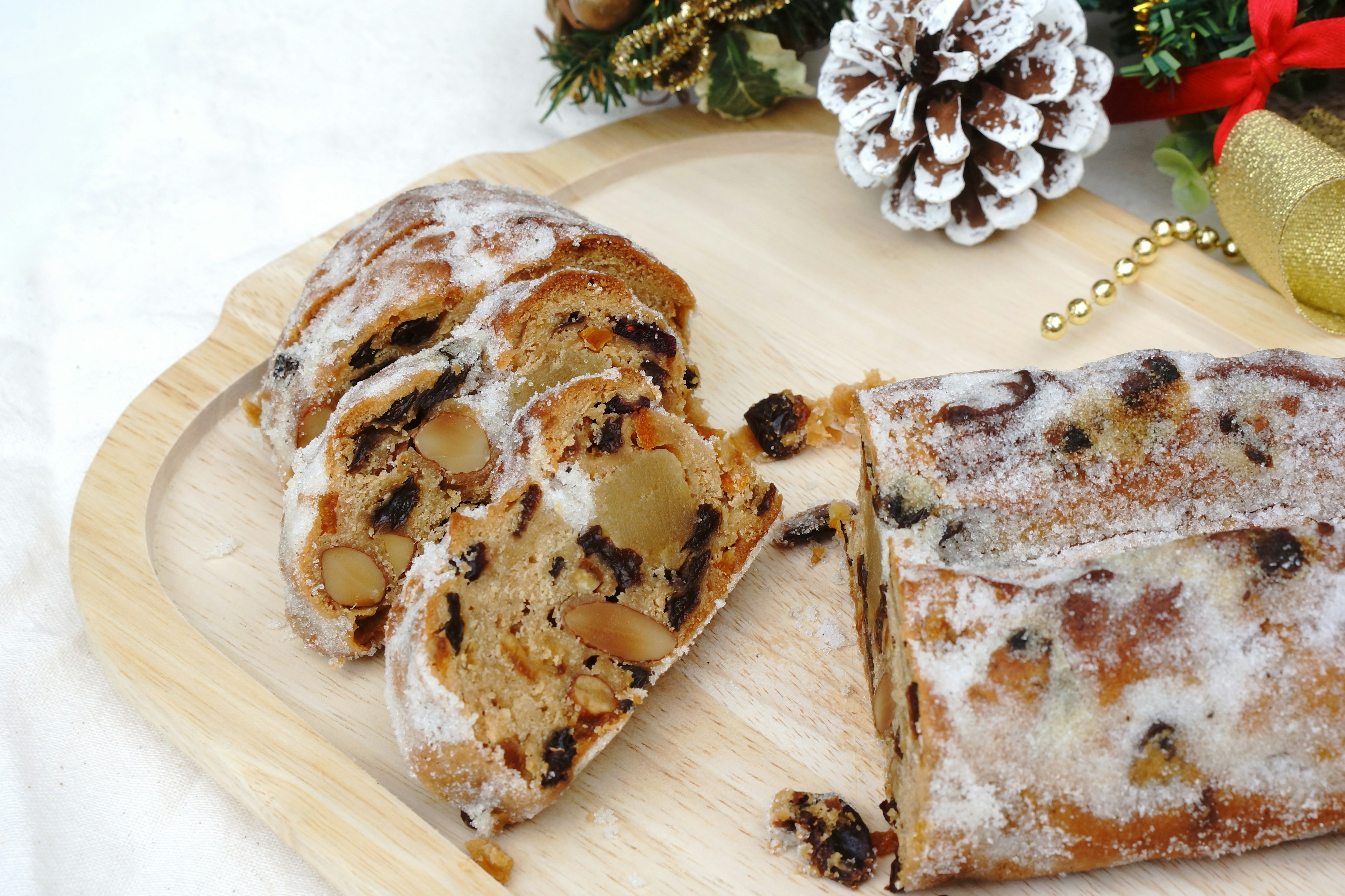 Sliced stollen on a wooden tray adorned with Christmas decorations