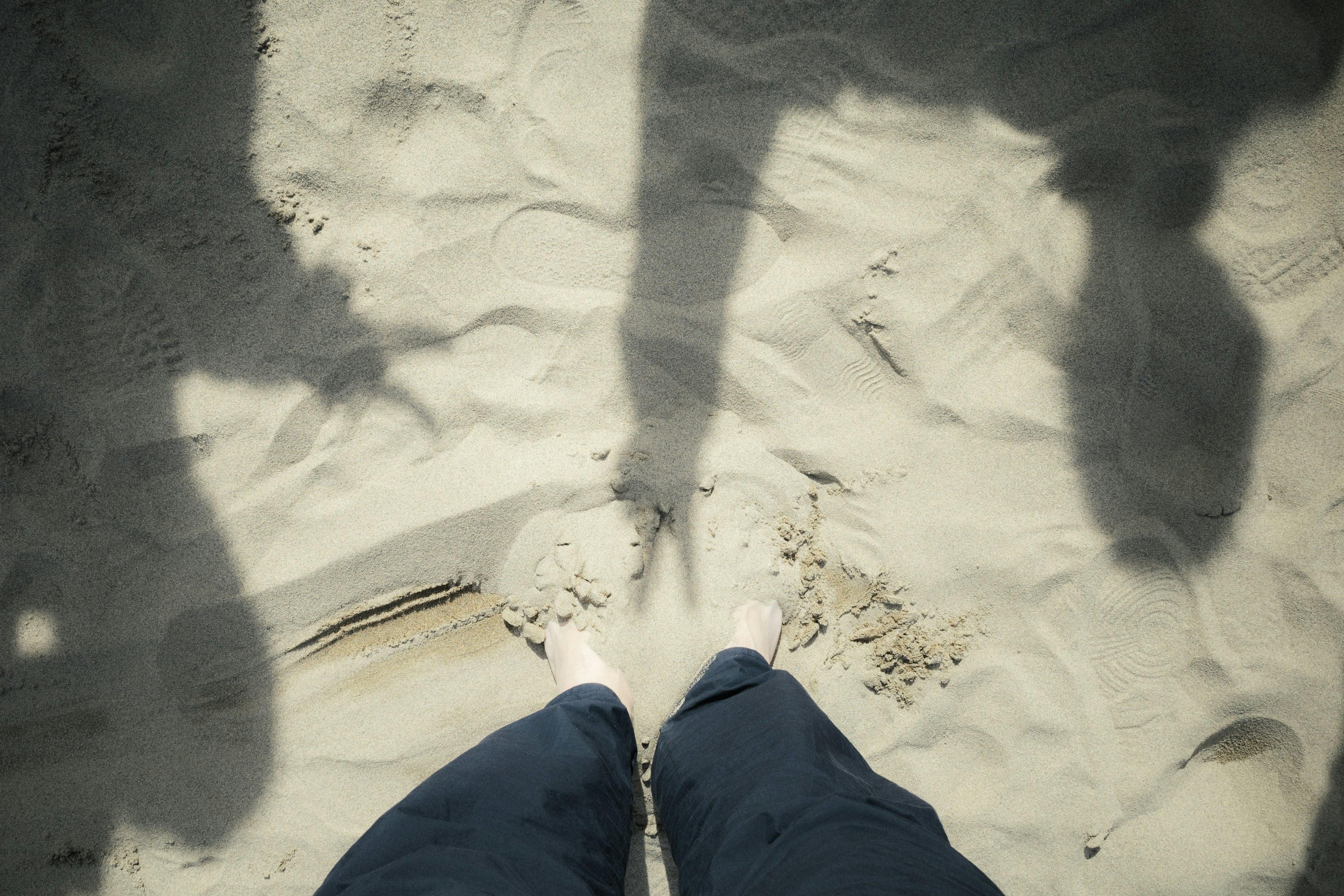 Photo de pieds dans le sable avec des ombres visibles