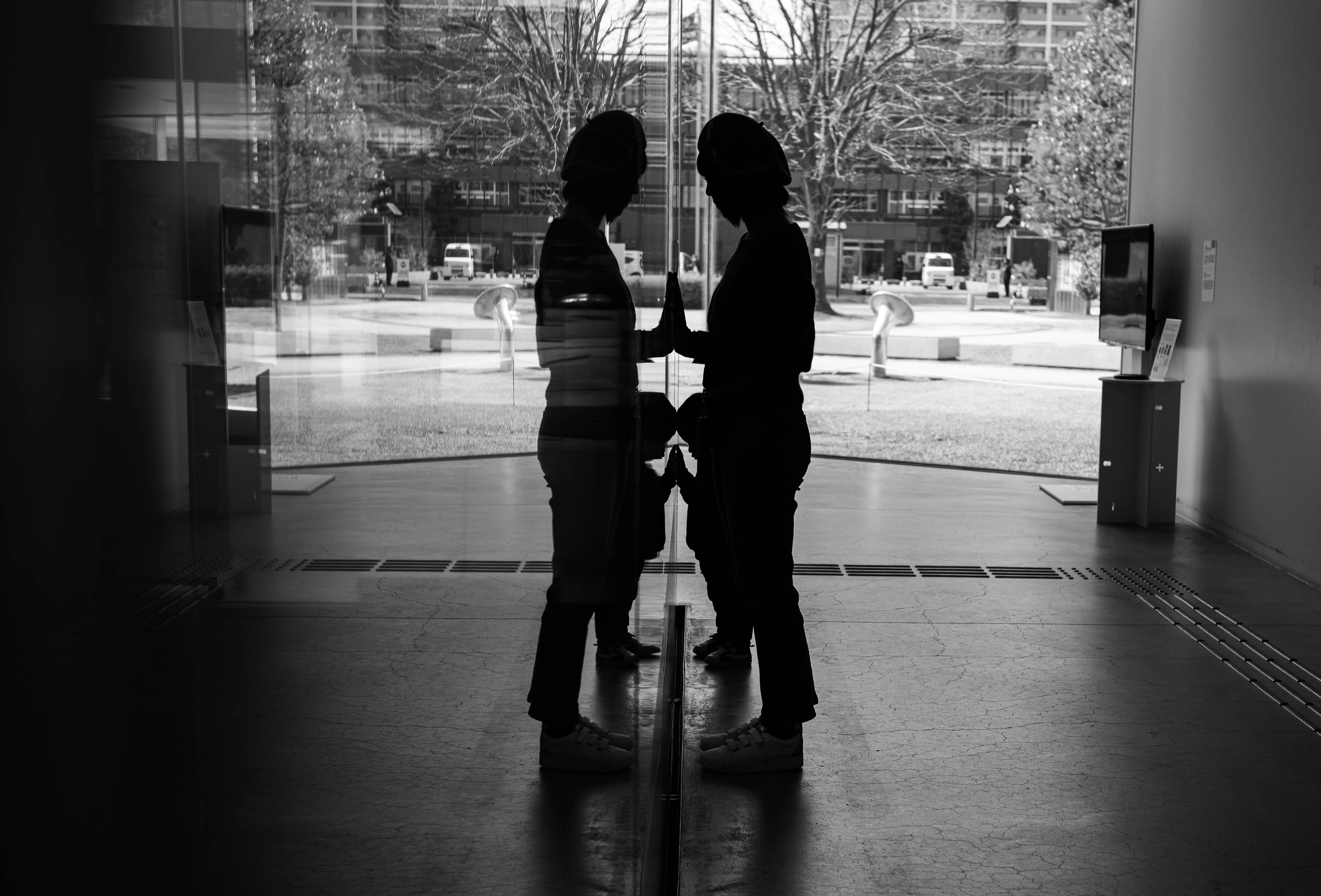 Black and white photo of two silhouettes standing in front of a glass door