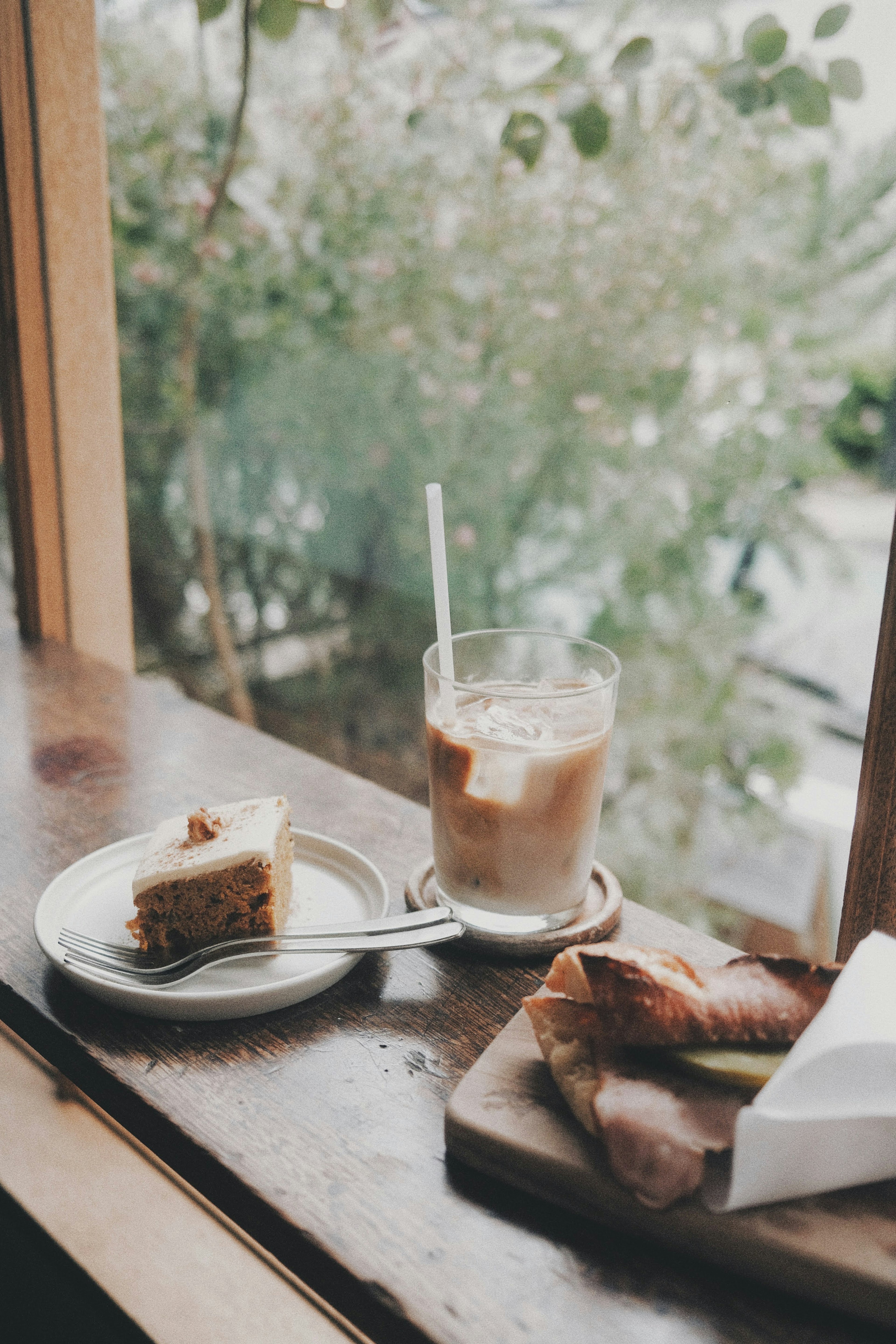 窓辺に置かれたアイスコーヒーとケーキのプレート