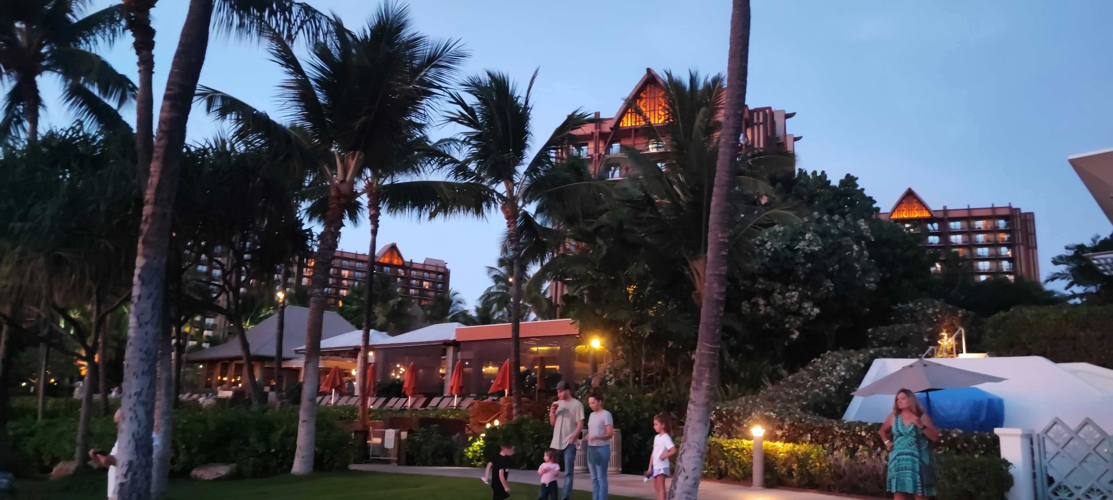 Evening view of a resort hotel with palm trees and families