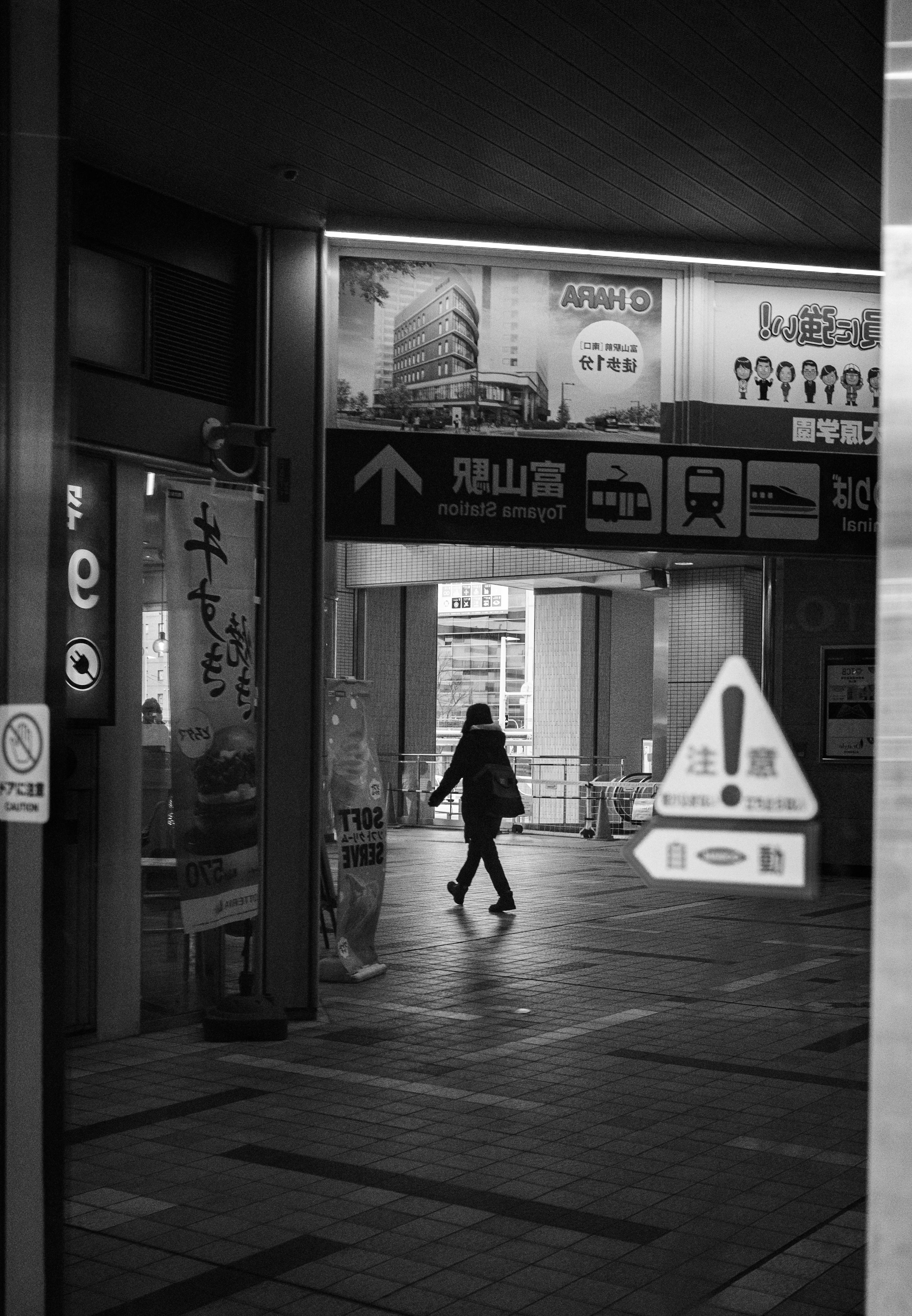 白黒の都市風景で、横断歩道を歩く人が写っている