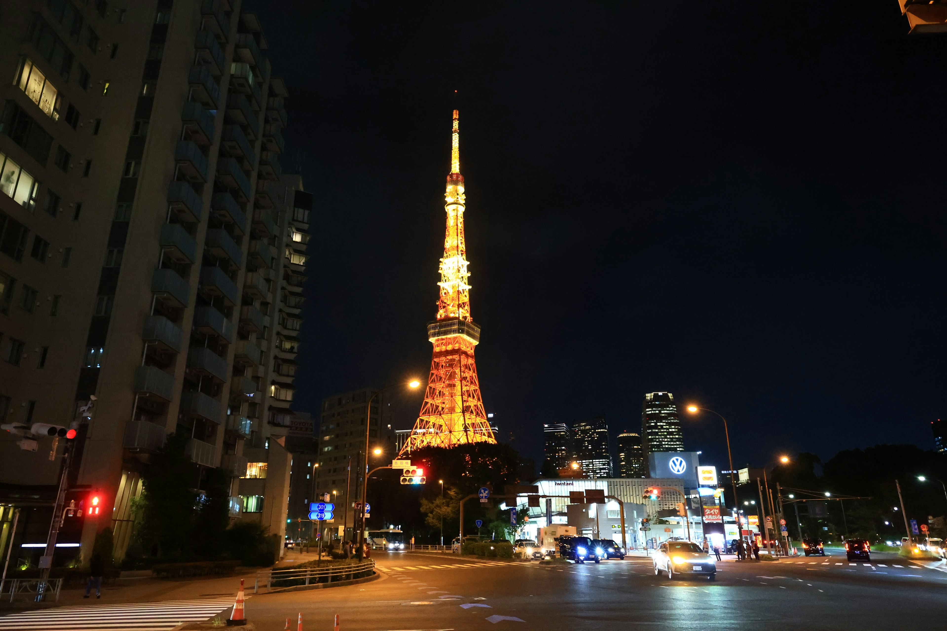 東京塔在夜間照亮，周圍有建築