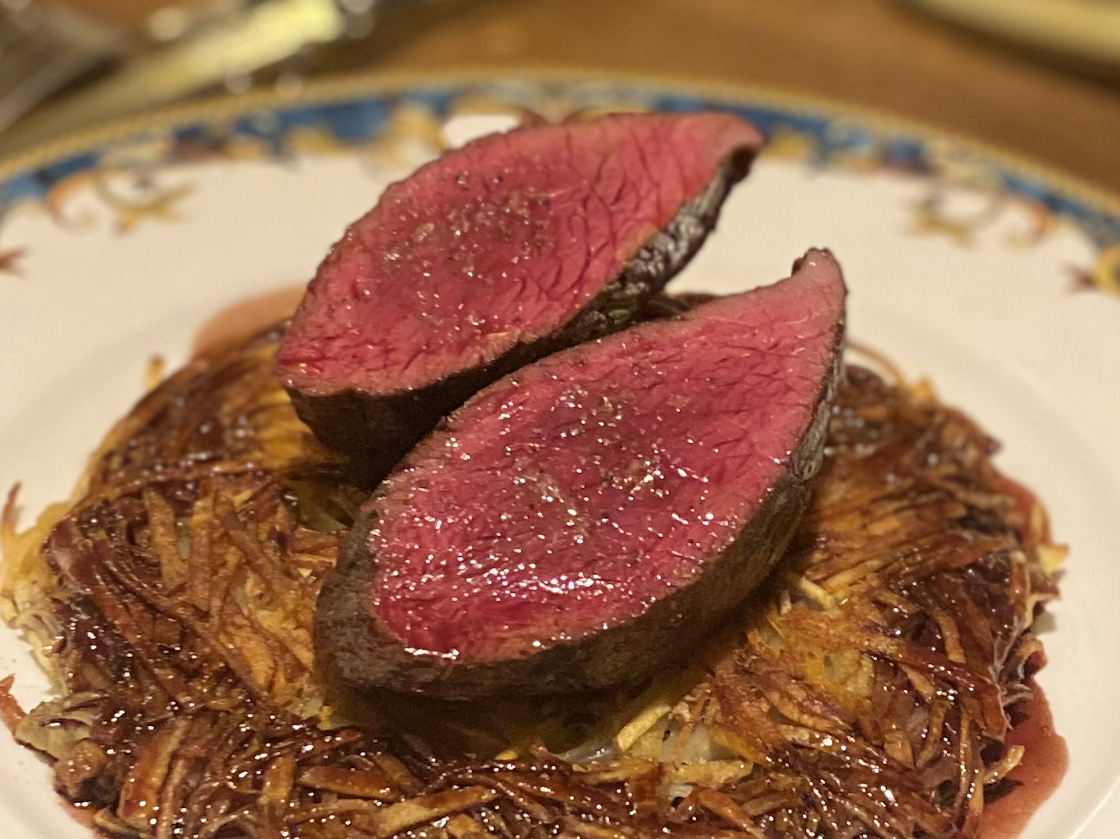 Carne de res en rodajas servida en un plato con papas hash brown