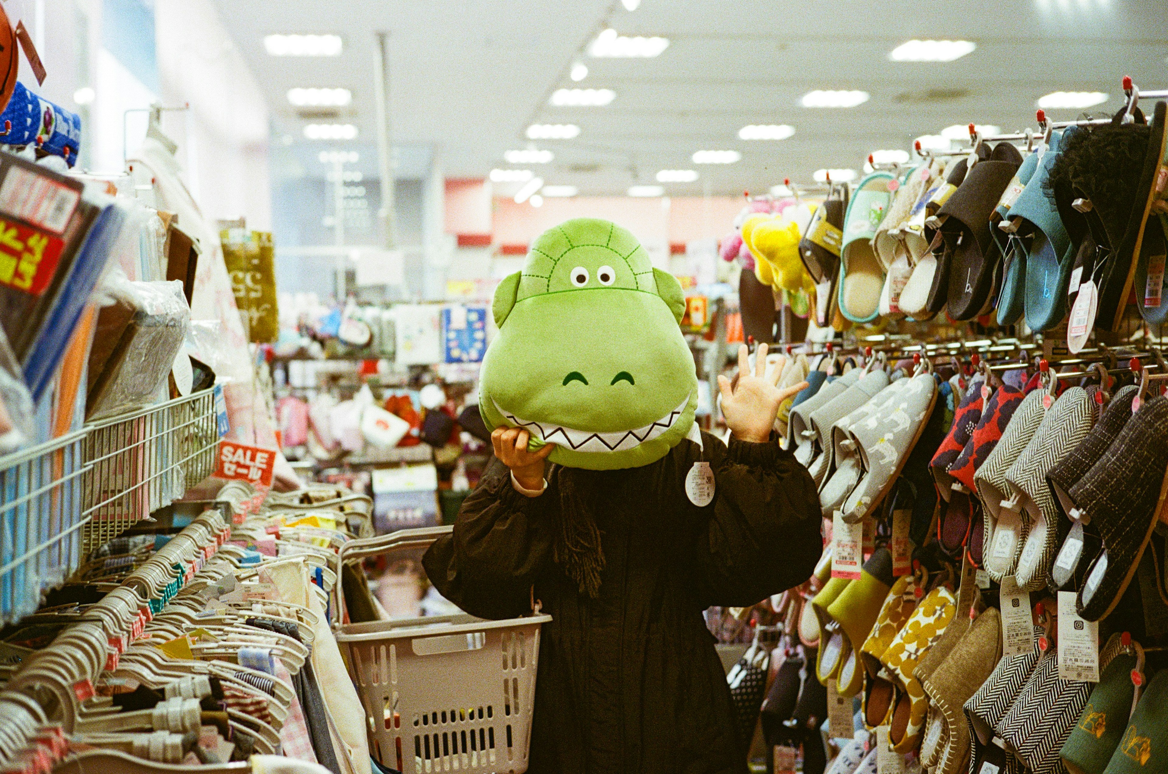 Persona con un sombrero de cabeza de dinosaurio saludando en un pasillo de tienda