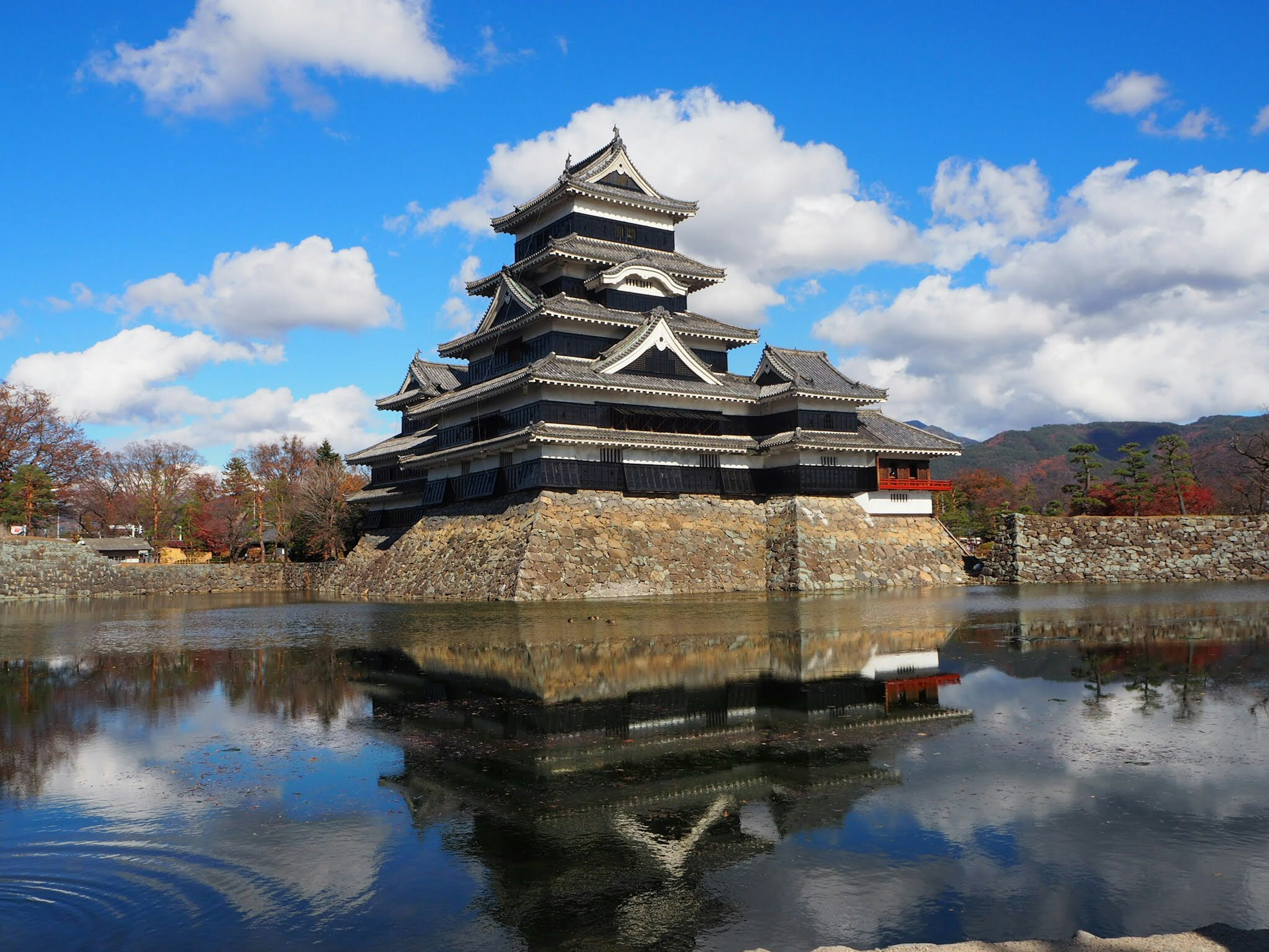 Vista panoramica del Castello di Matsumoto che si riflette nell'acqua sotto un cielo blu