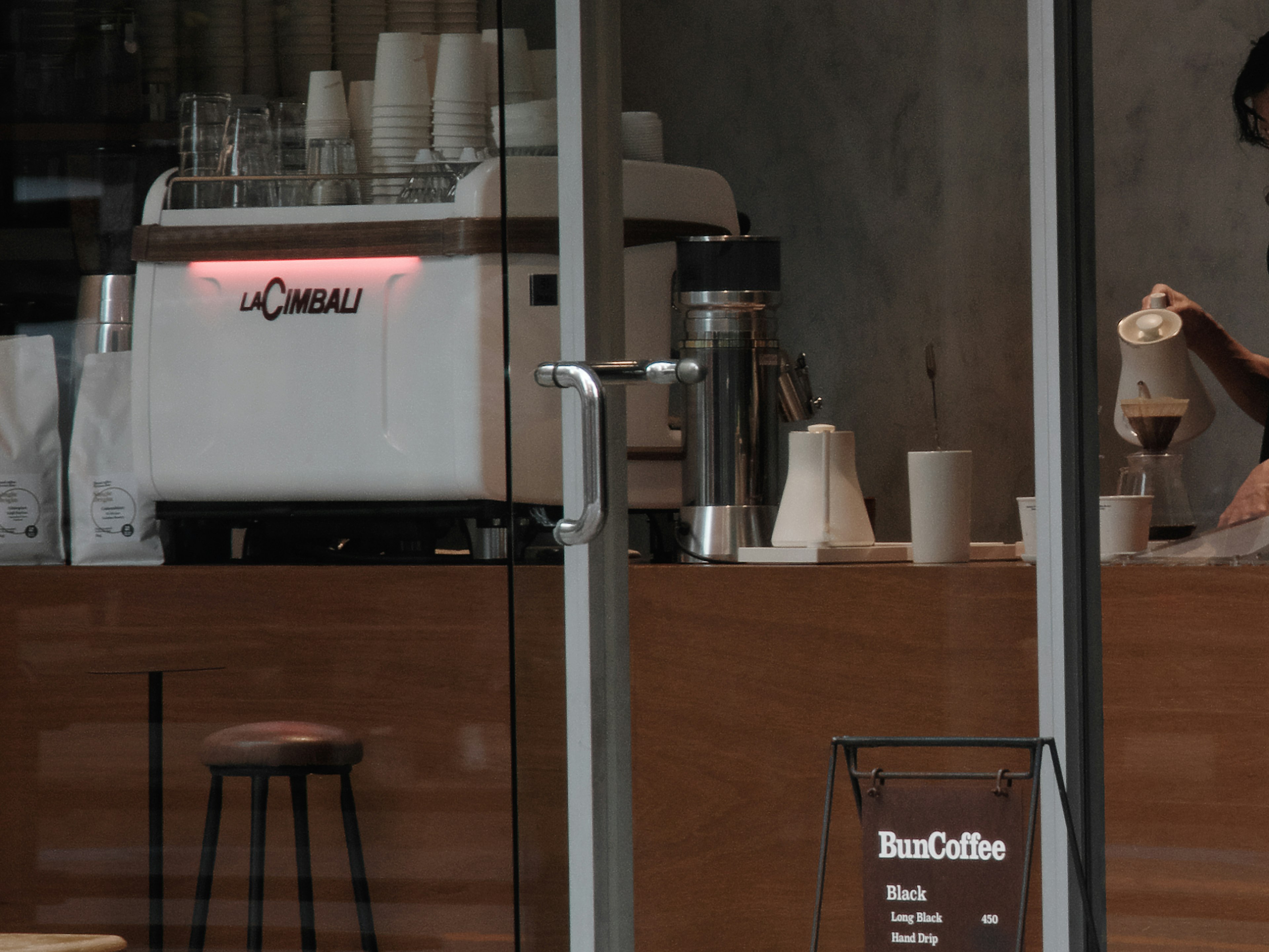 A café counter featuring an espresso machine and a barista pouring coffee