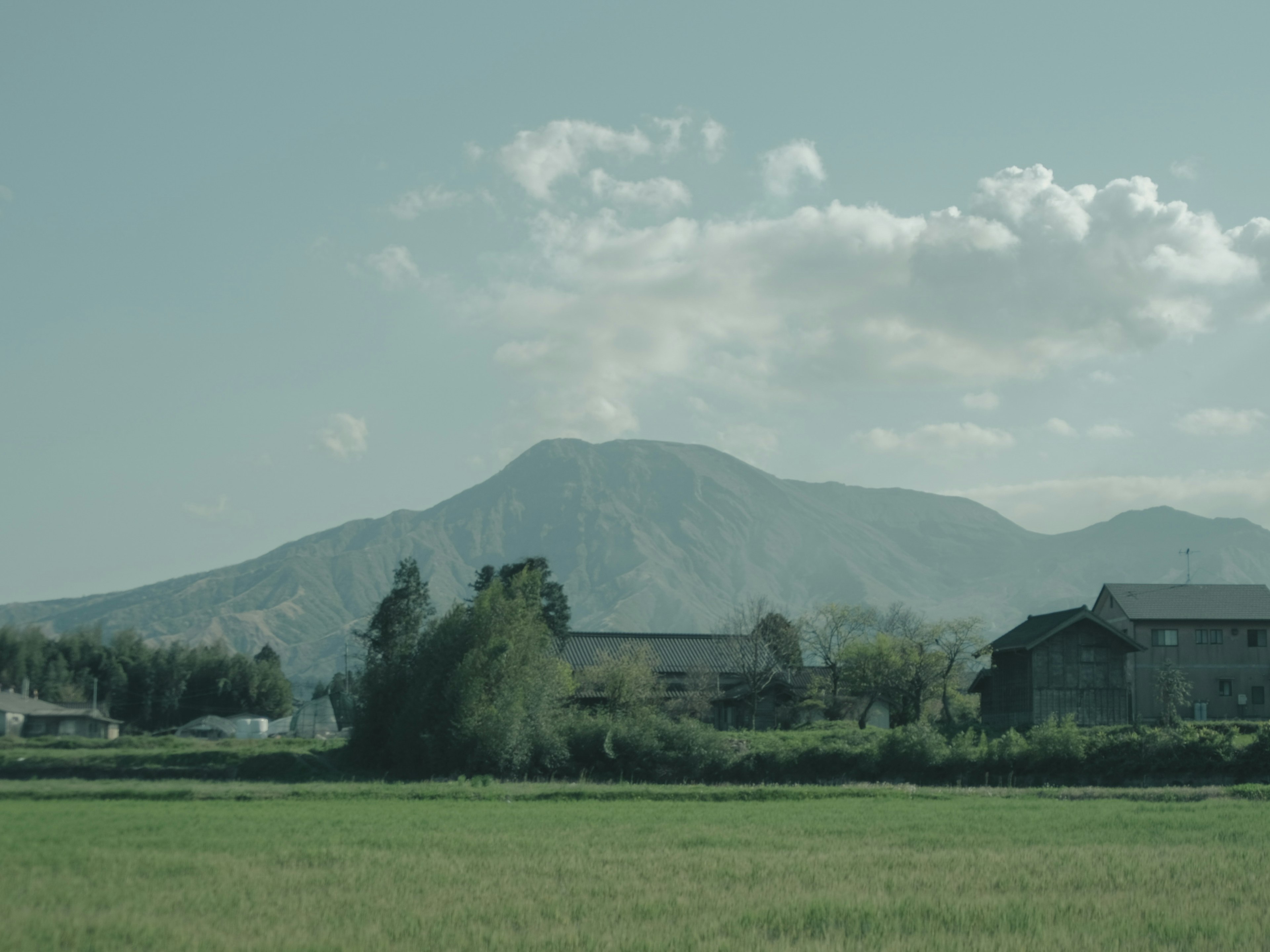 Montagne se levant au-dessus d'un paysage rural avec des nuages dans le ciel