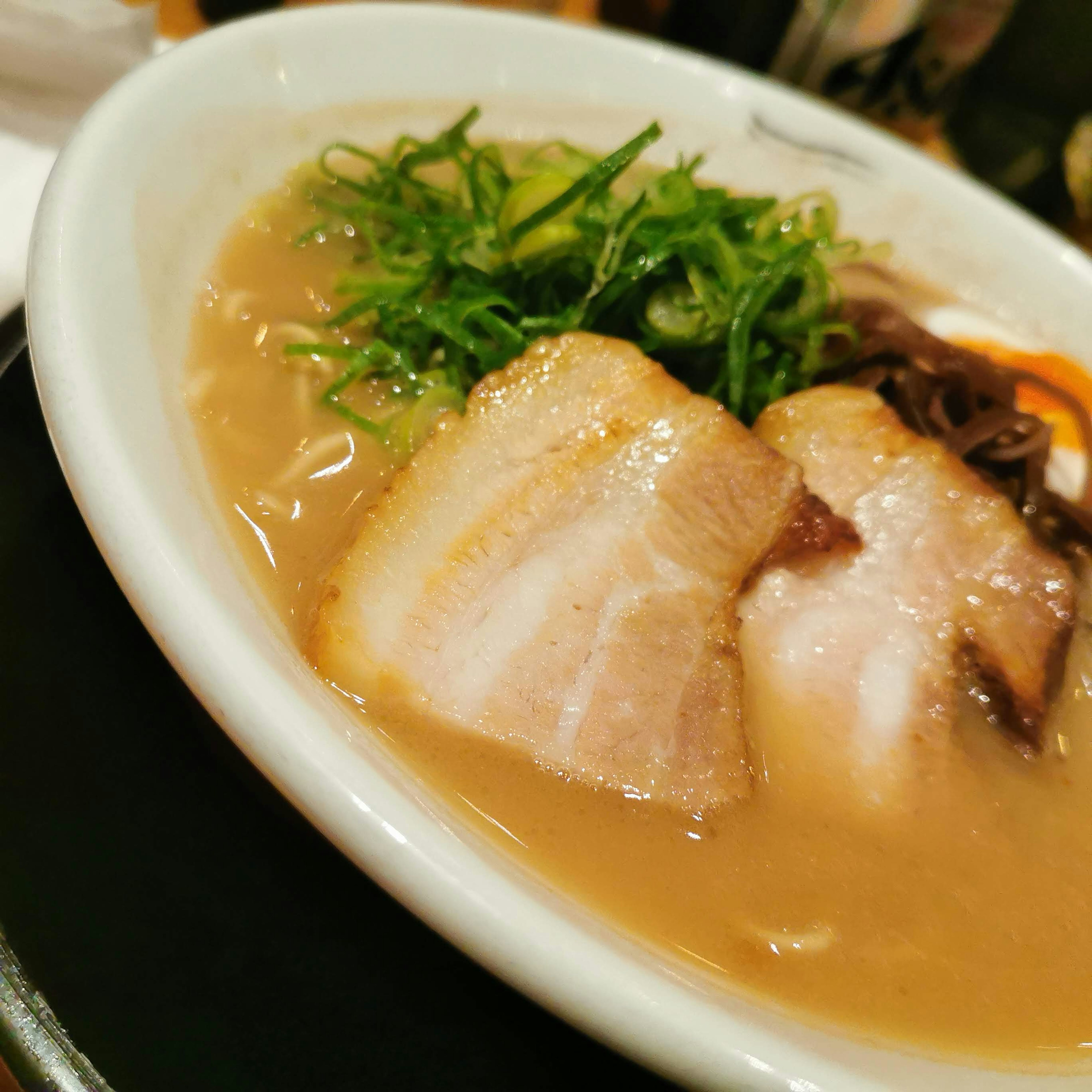 Tazón de ramen con rodajas de chashu y cebollas verdes encima