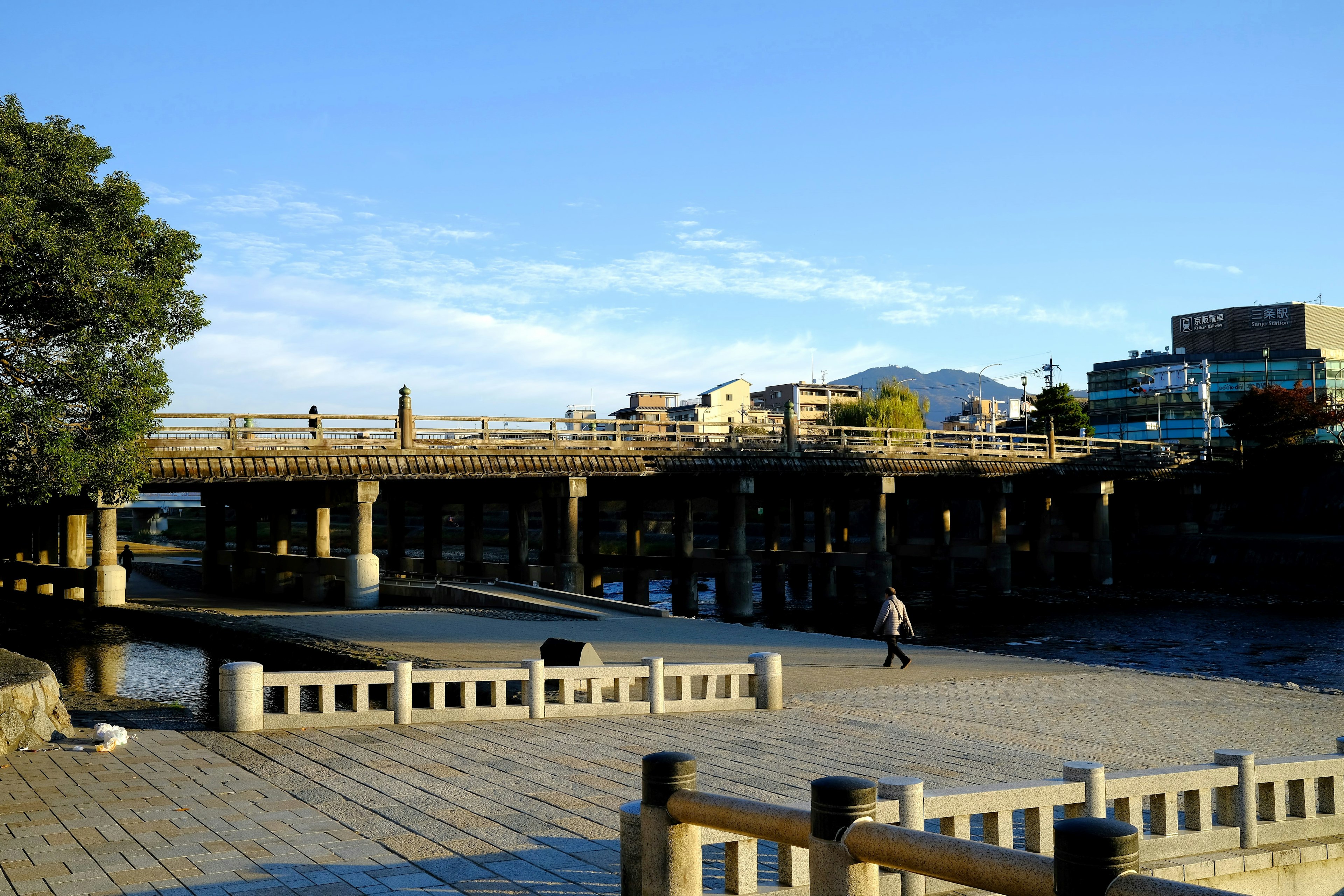 Vue pittoresque d'un pont sur une rivière sous un ciel bleu avec une personne marchant