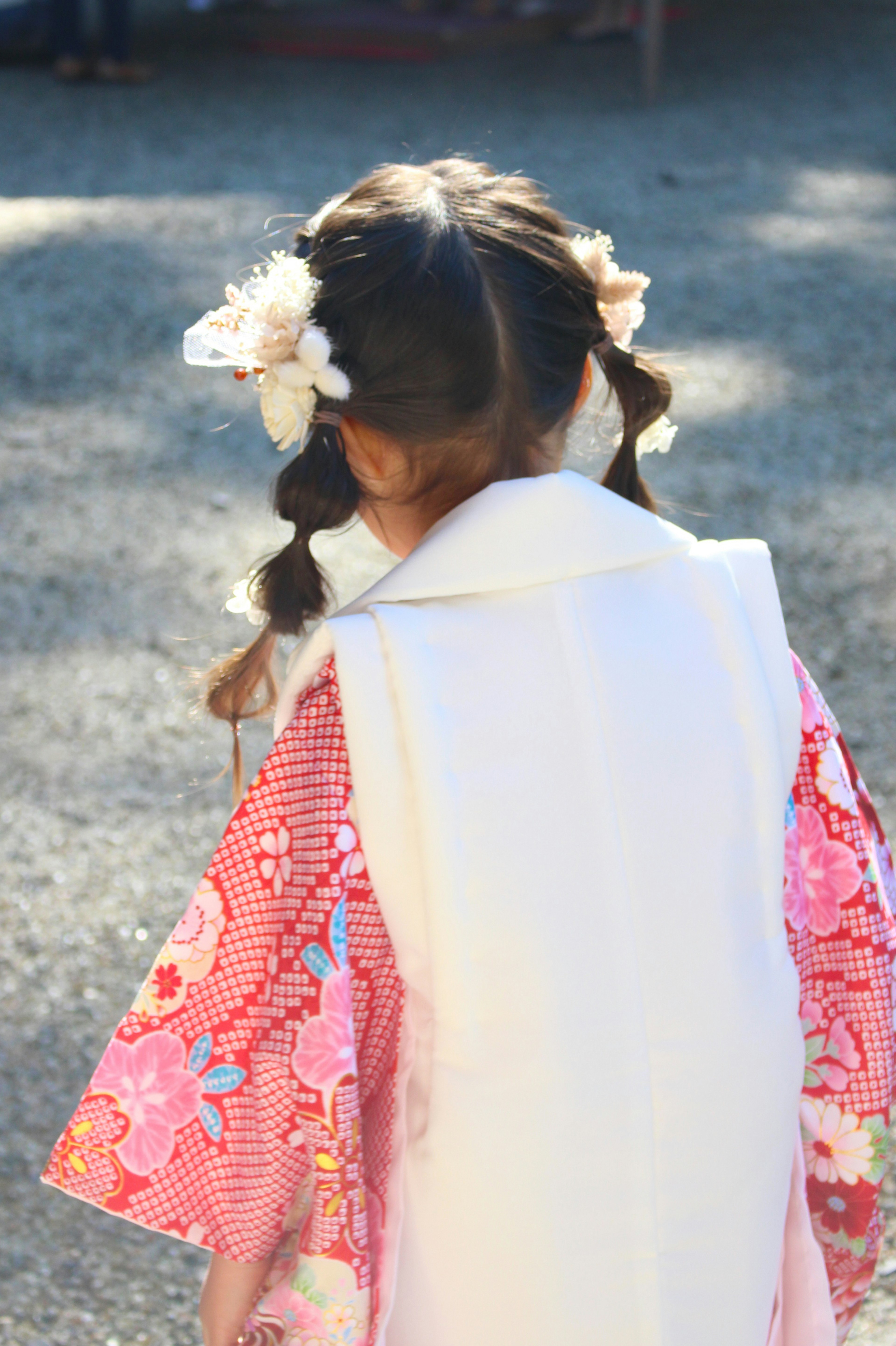 Ein Mädchen in einem traditionellen Kimono mit einem floralen Haarschmuck von hinten gesehen