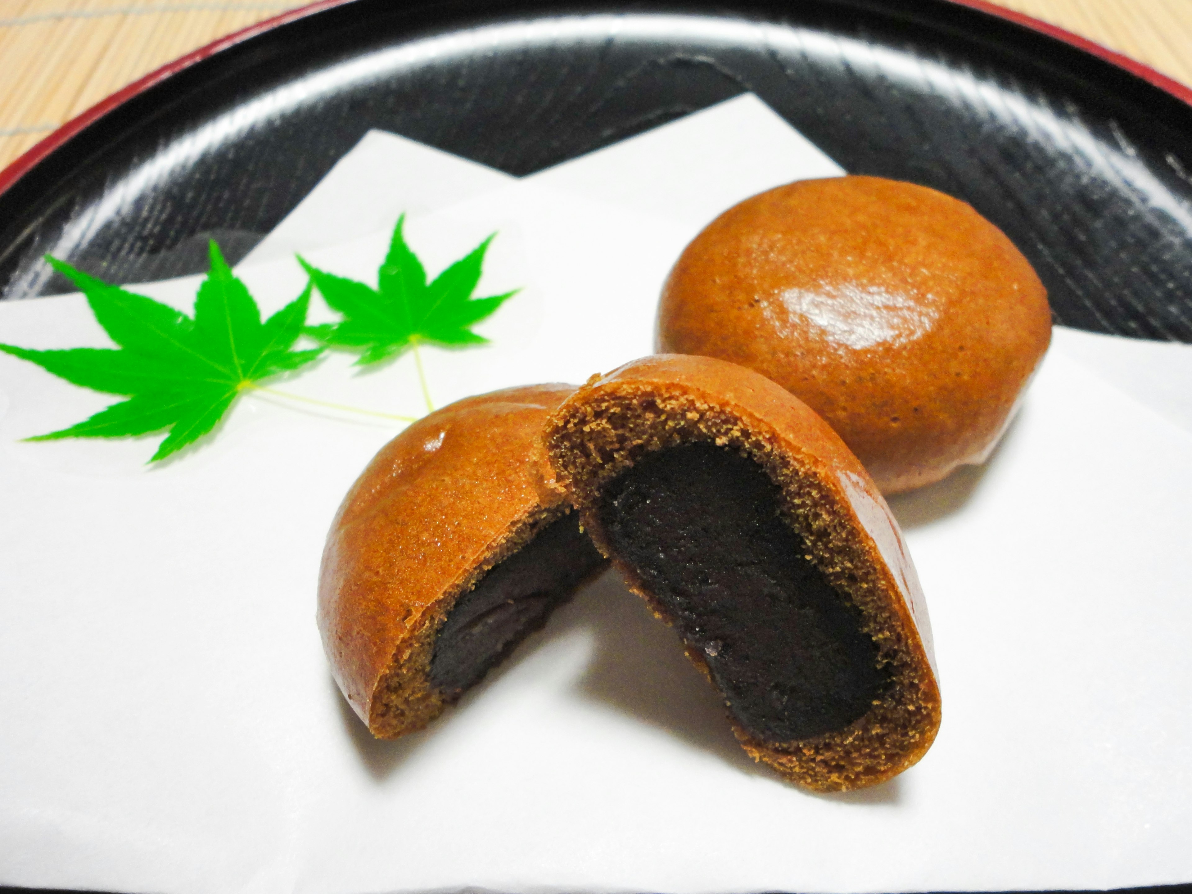 Two sweet Japanese confections filled with red bean paste placed on white paper