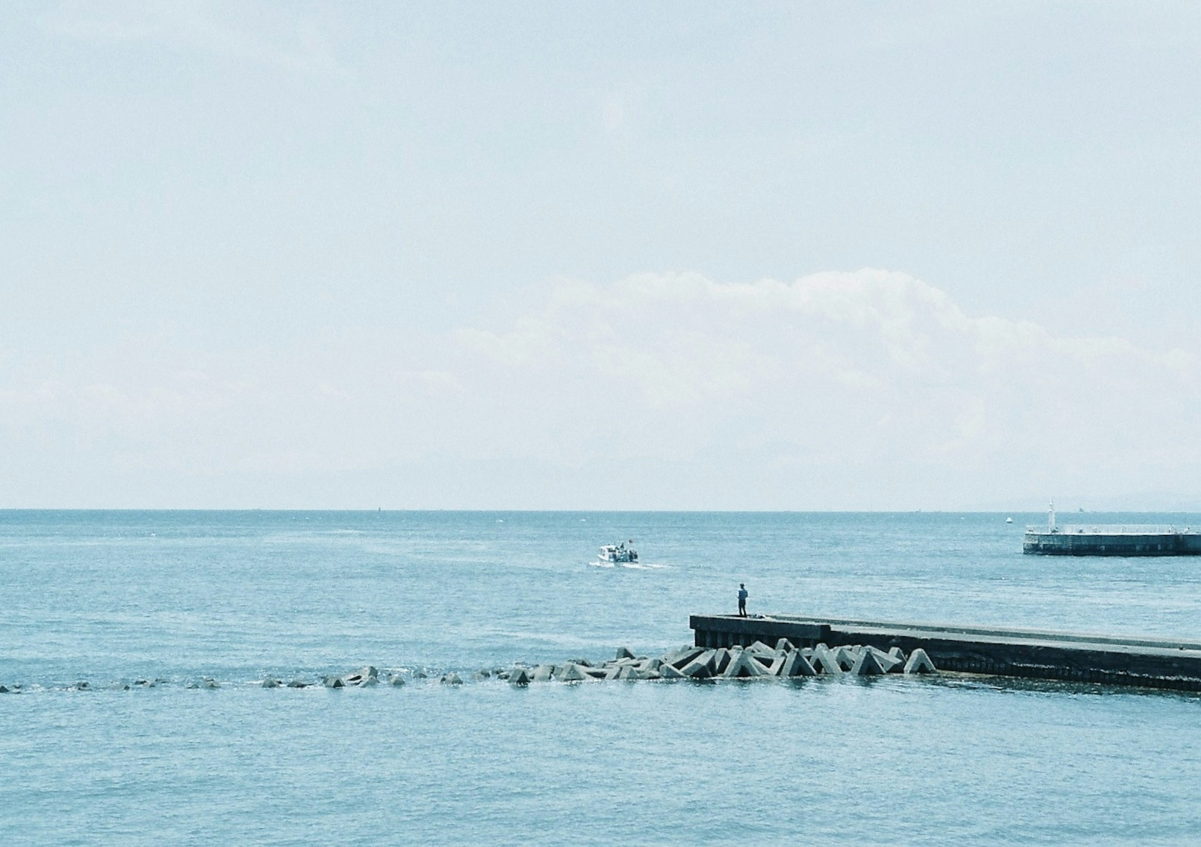 Calm sea and sky with a small boat and a person visible