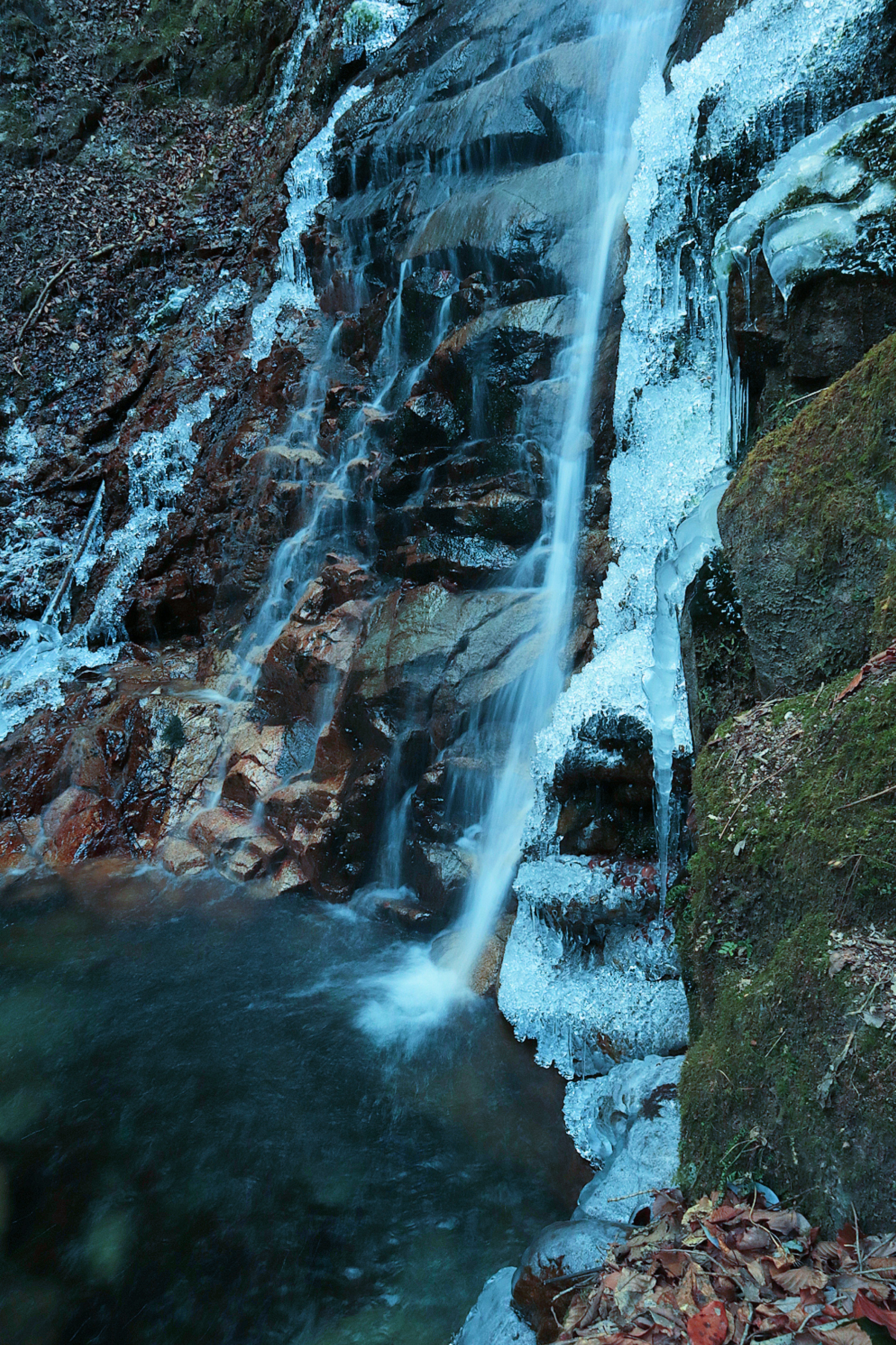 Bild eines gefrorenen Wasserfalls umgeben von Felsen