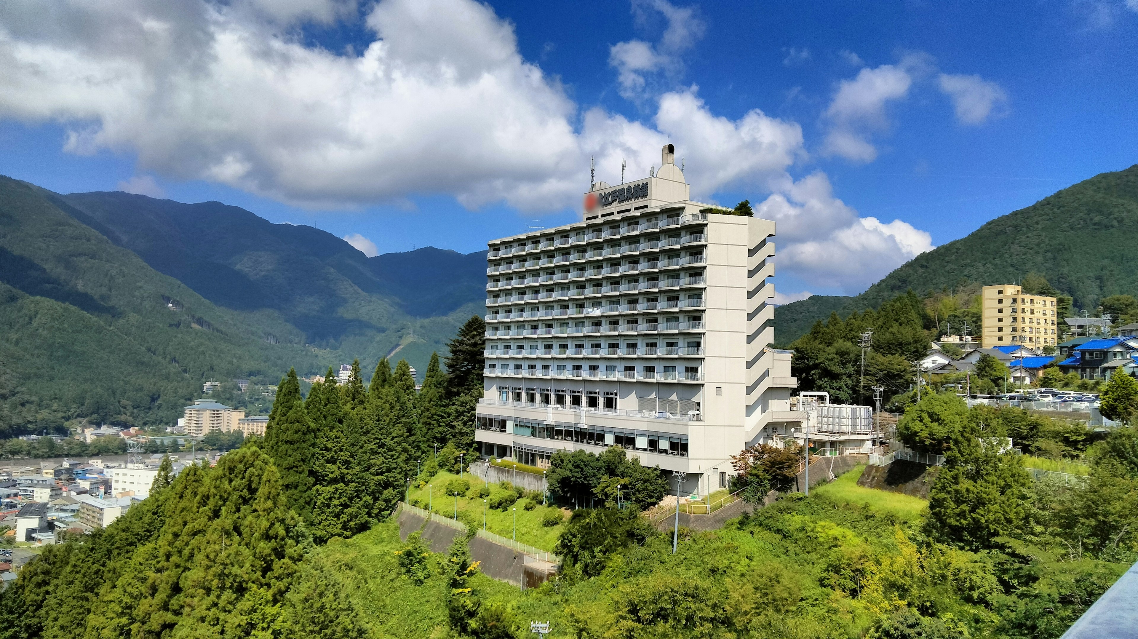 Hotel rodeado de montañas con cielo azul y nubes blancas