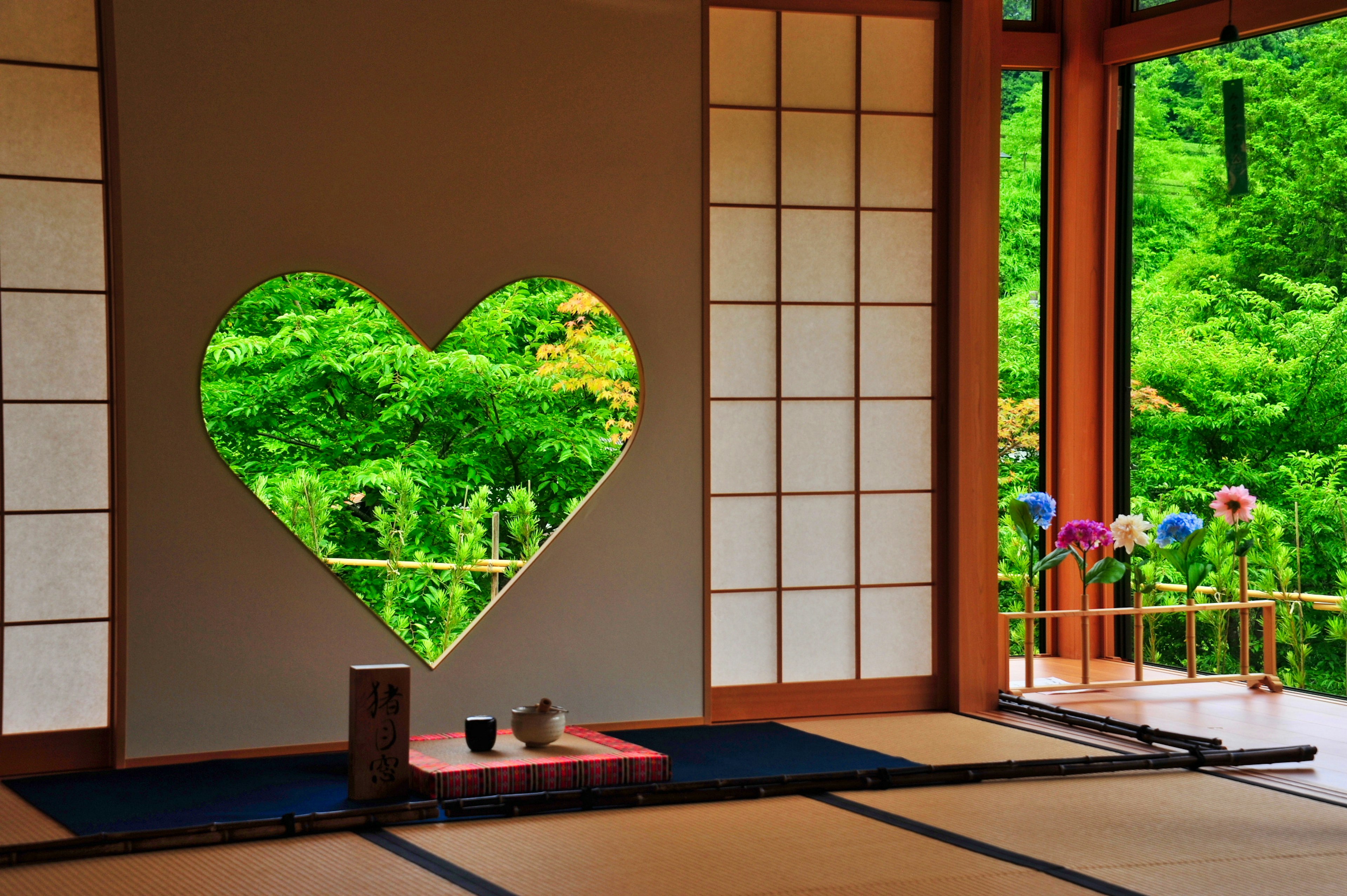 Stanza giapponese tradizionale con una finestra a forma di cuore che mostra un paesaggio verde