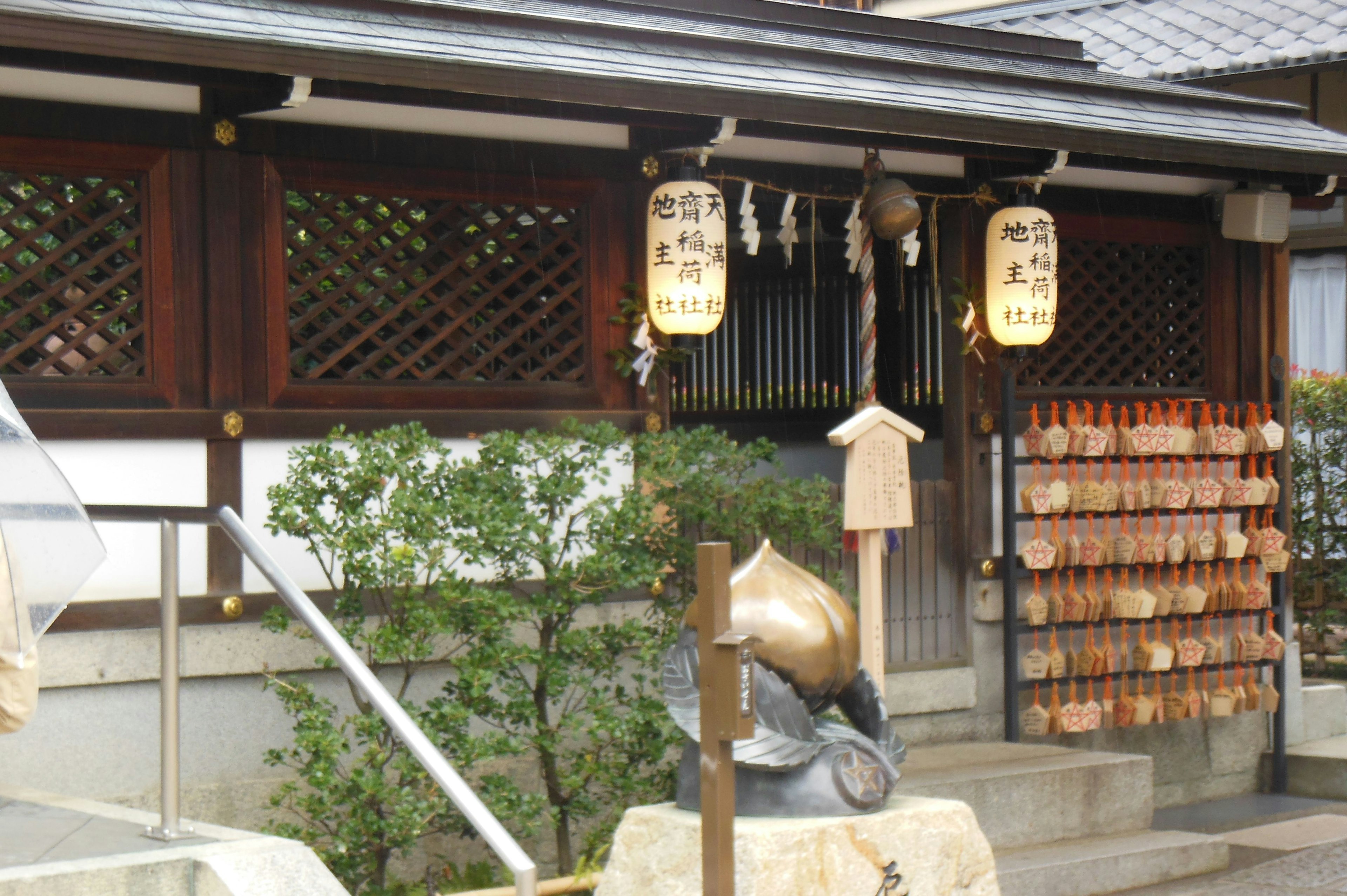 Exterior de un santuario japonés tradicional con faroles colgantes y tablillas de ema de madera