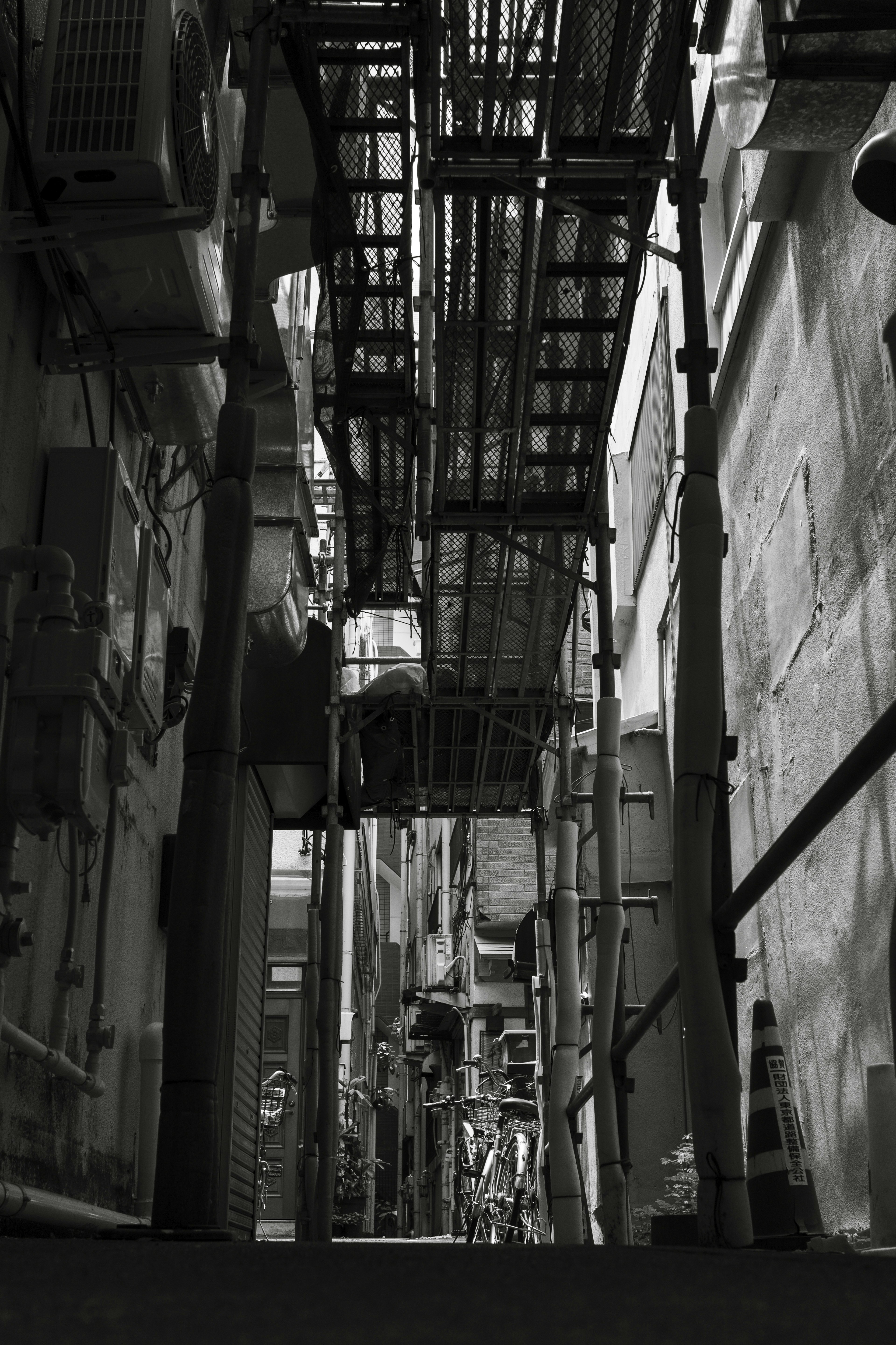 Black and white image of a narrow alley with scaffolding and walls