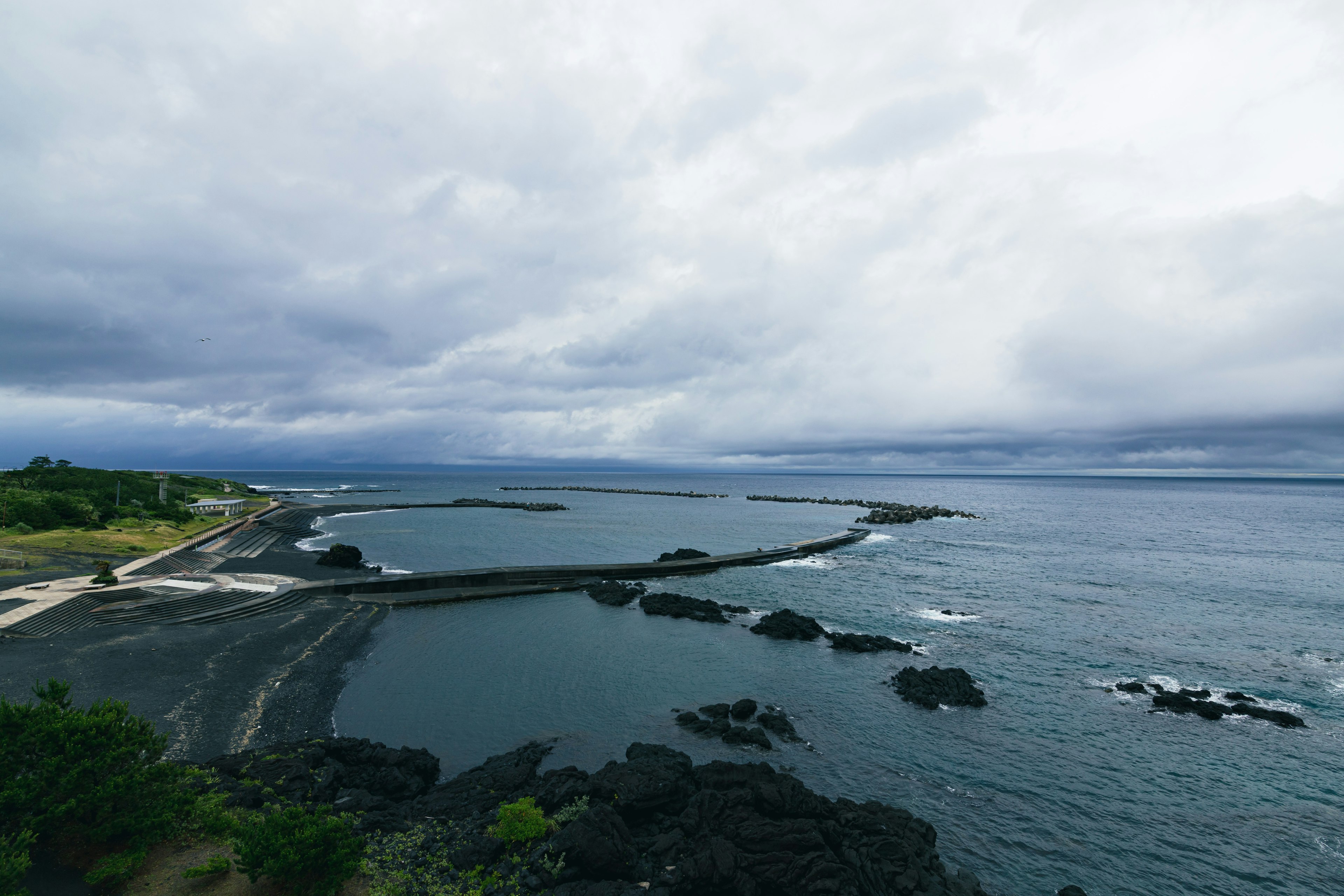 Une vue panoramique de l'océan avec des rochers et un ciel nuageux