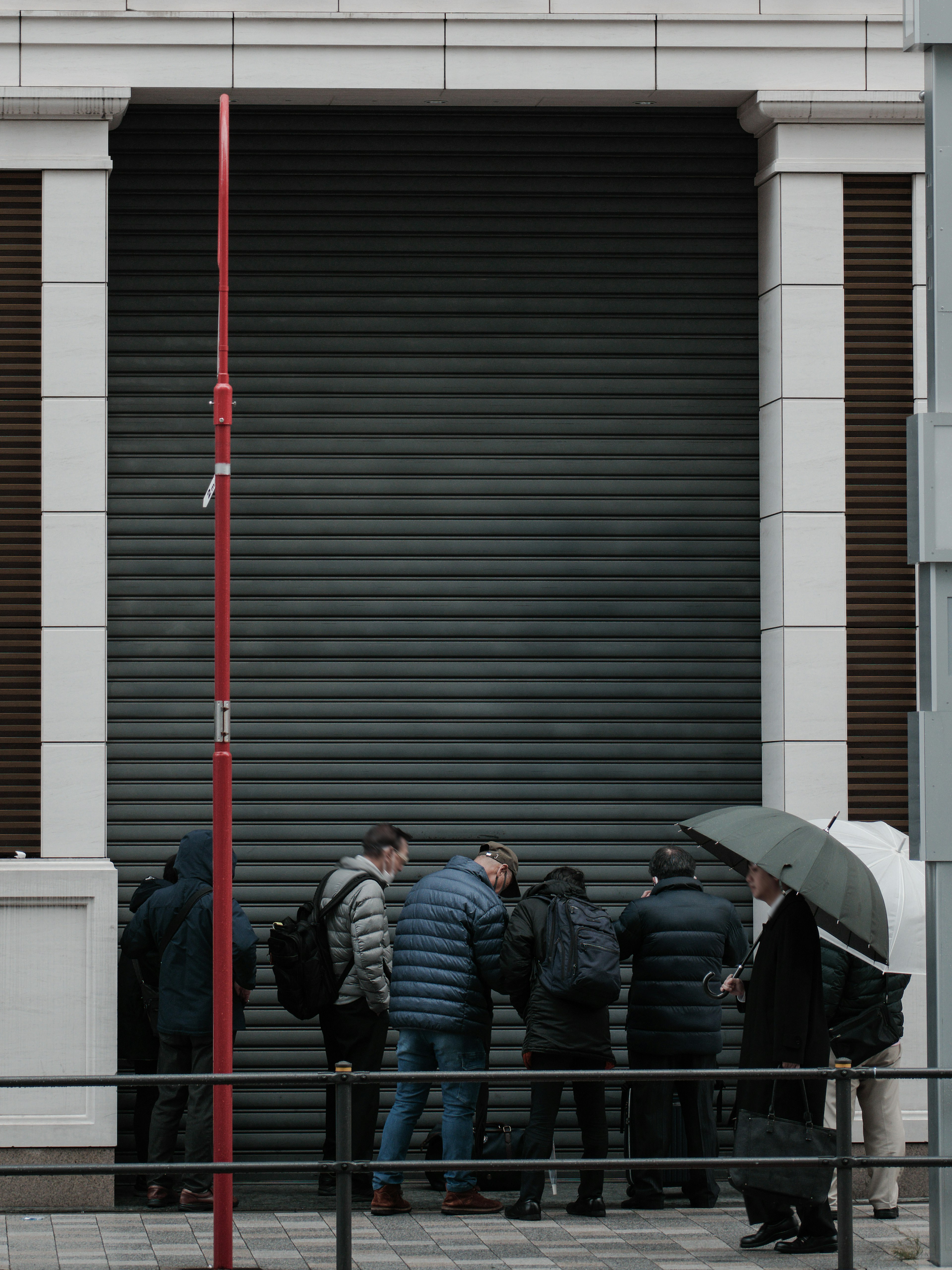 Un gruppo di persone riunite davanti a una serranda chiusa