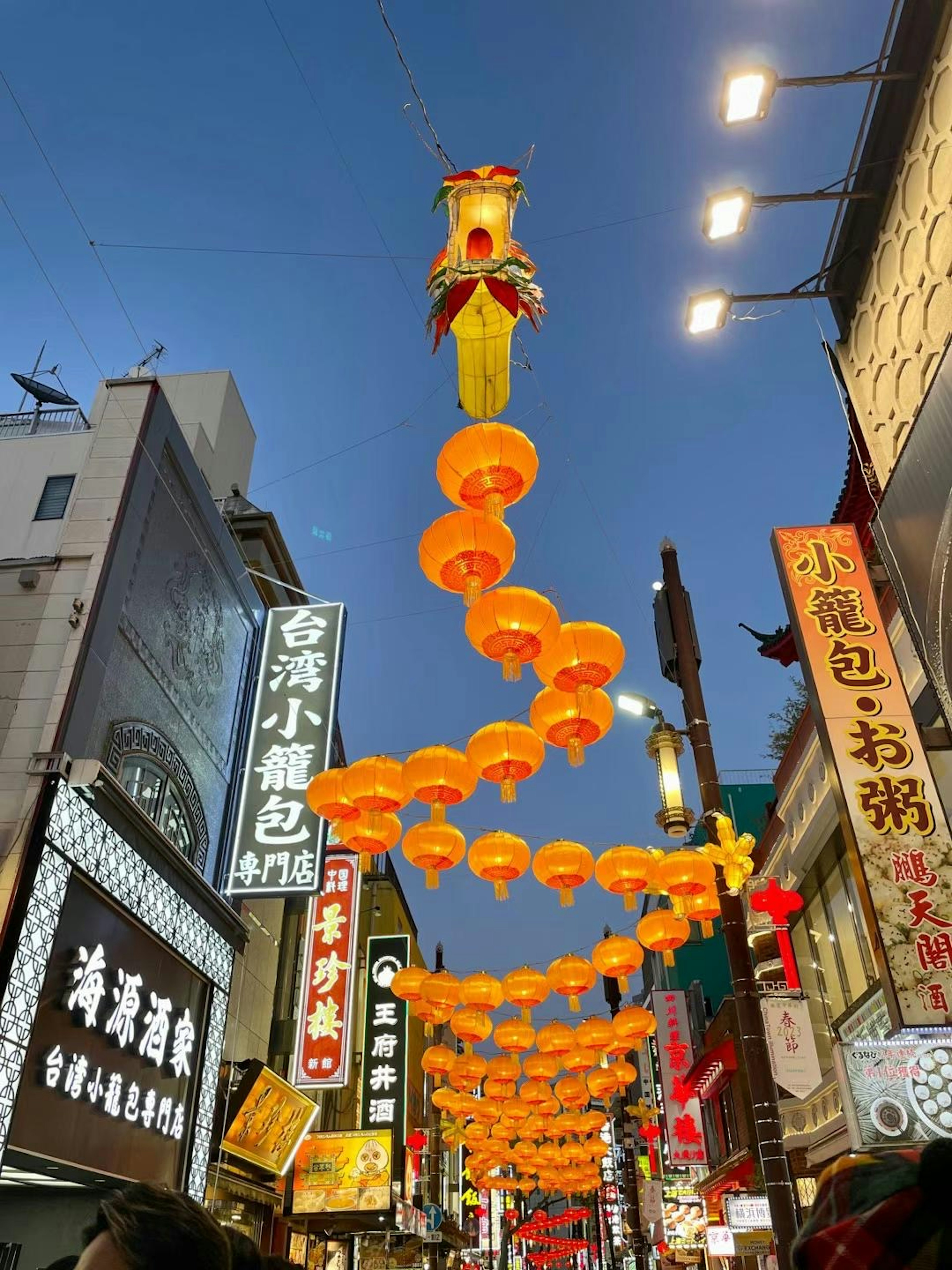 Calle adornada con faroles naranjas colgando en el cielo de la tarde