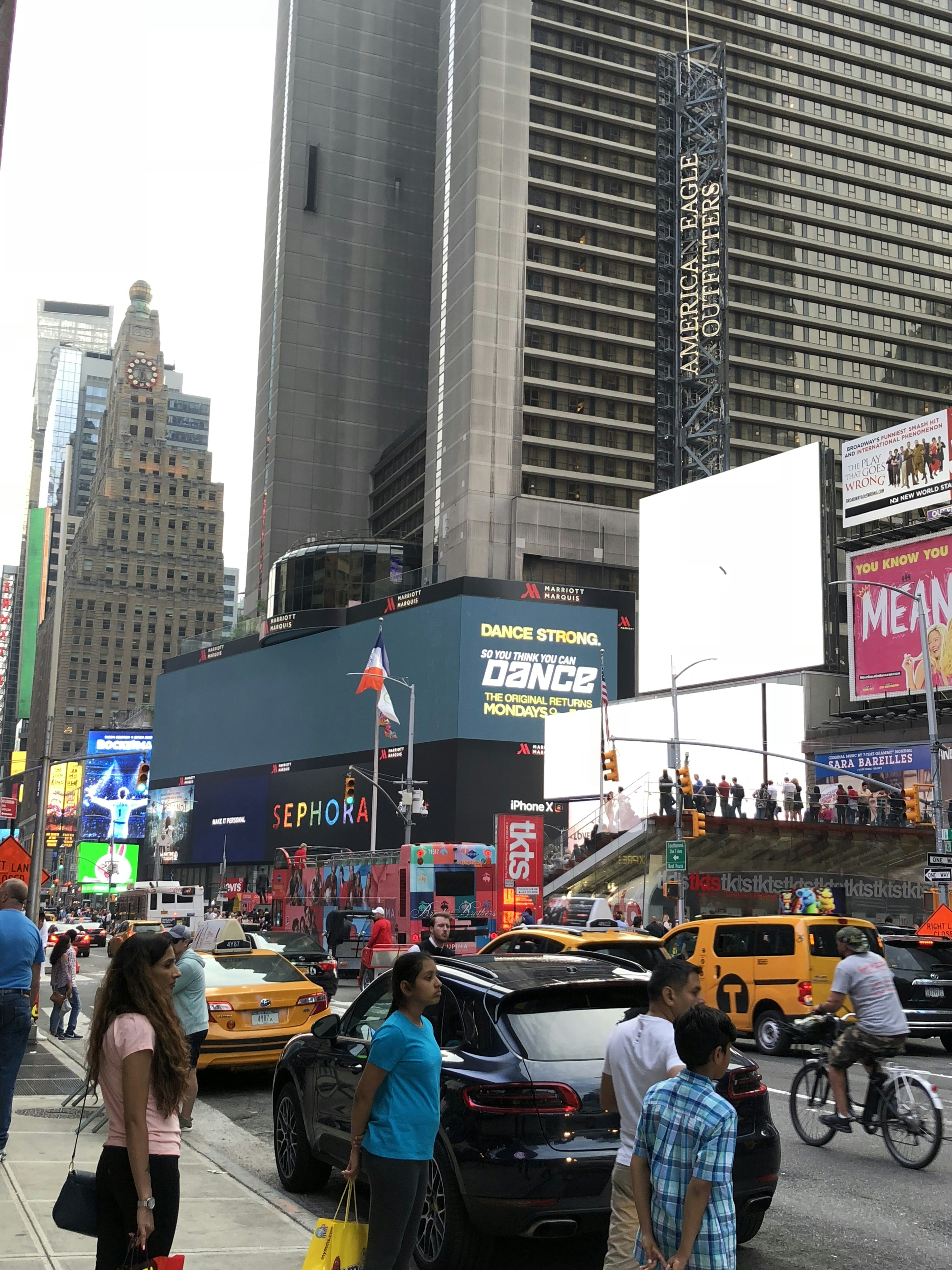 Escena animada de Times Square con taxis amarillos y peatones mostrando grandes vallas publicitarias