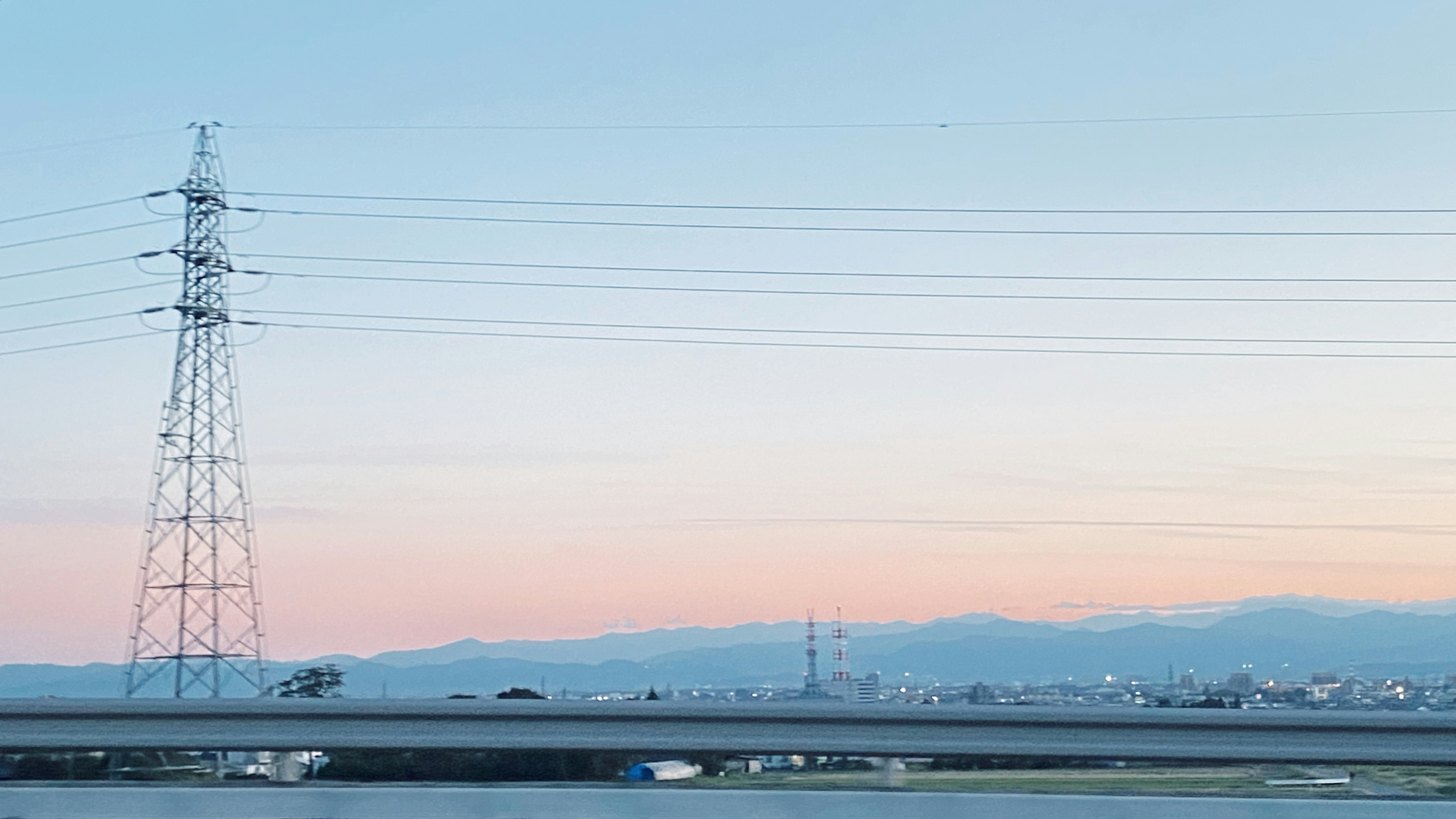 Paesaggio con linee elettriche e ponte sotto un cielo crepuscolare