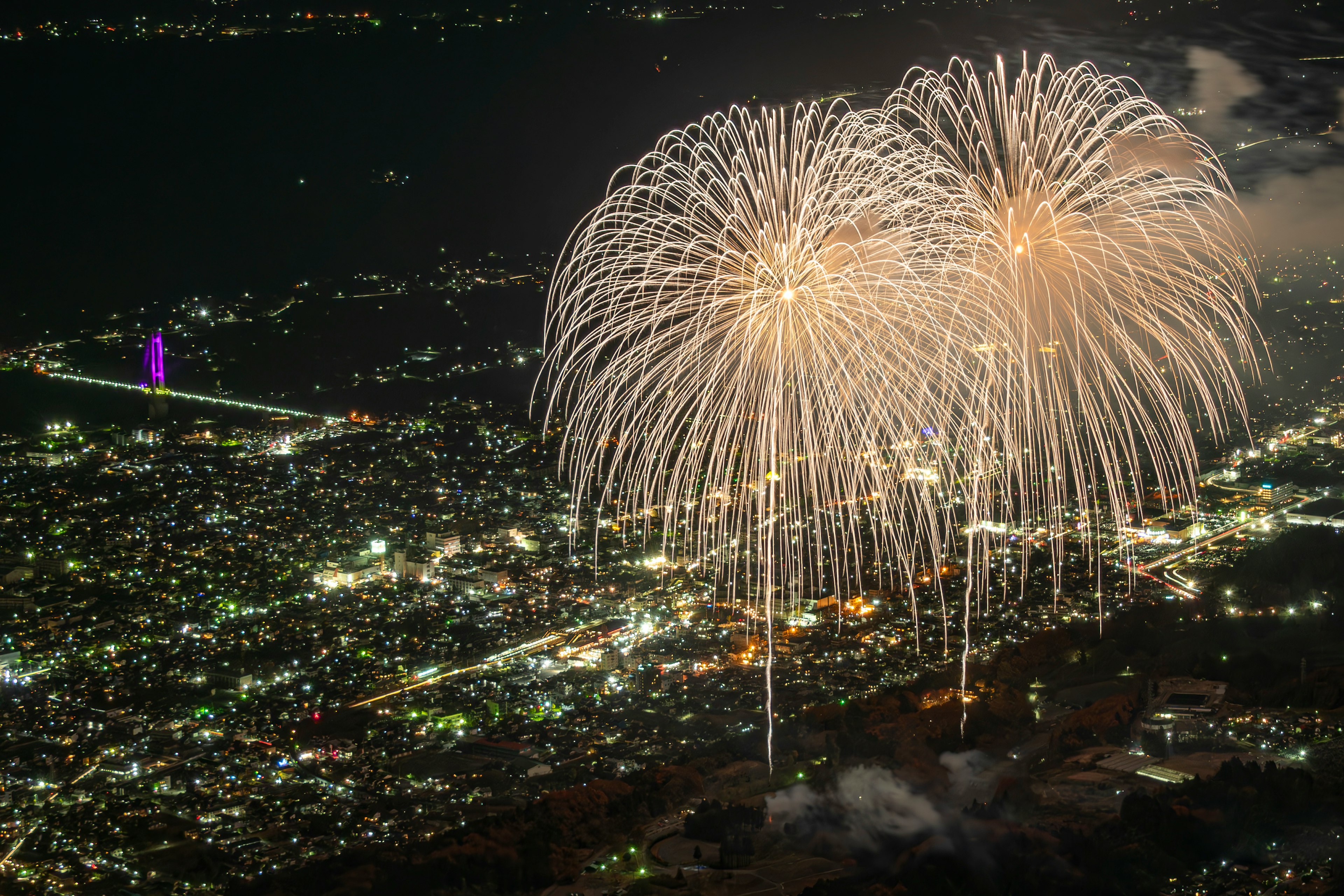 Des feux d'artifice éclatant au-dessus d'une ville la nuit avec des lumières brillantes