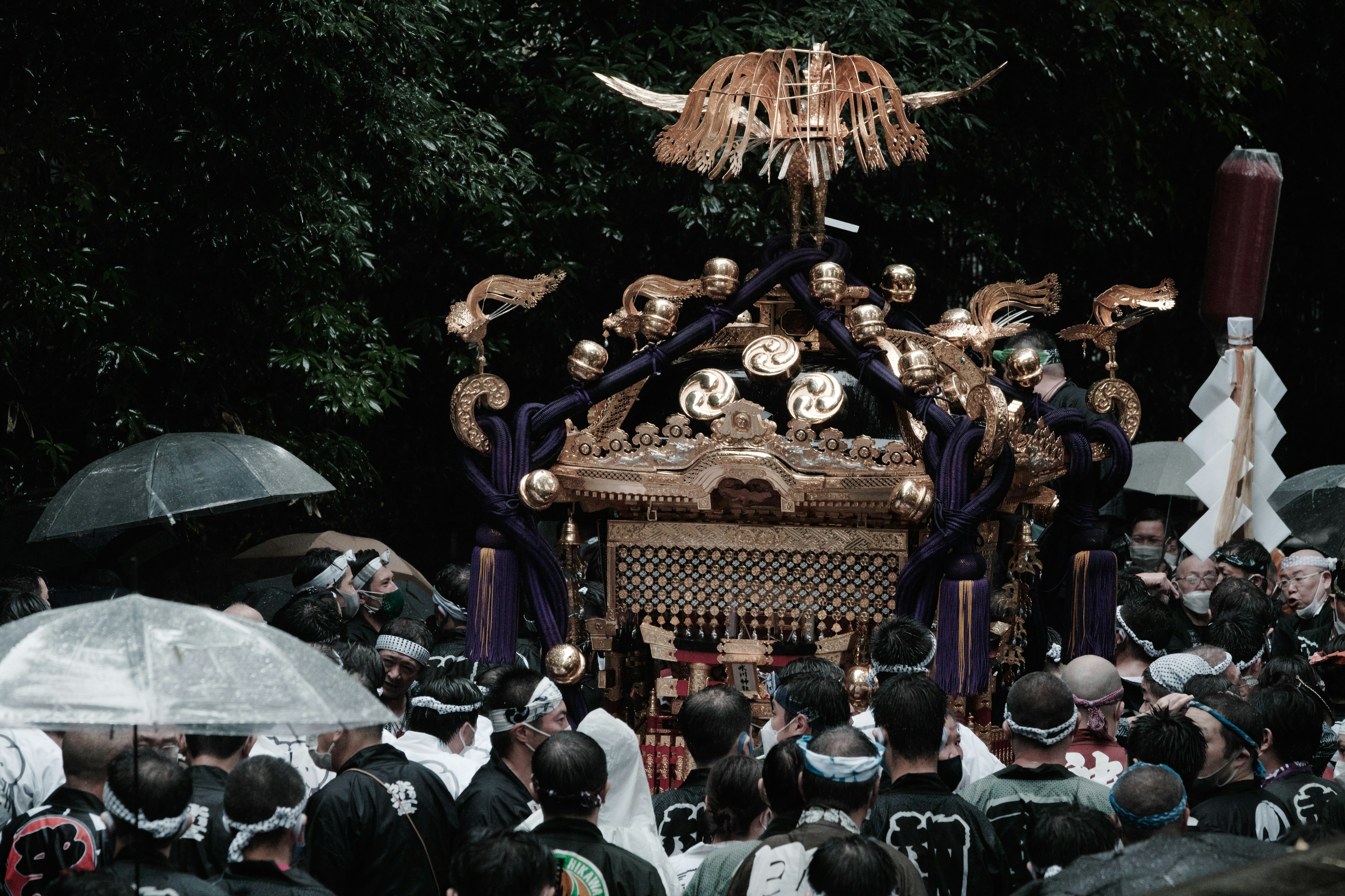 Multitud llevando un palanquín ceremonial con paraguas en un festival