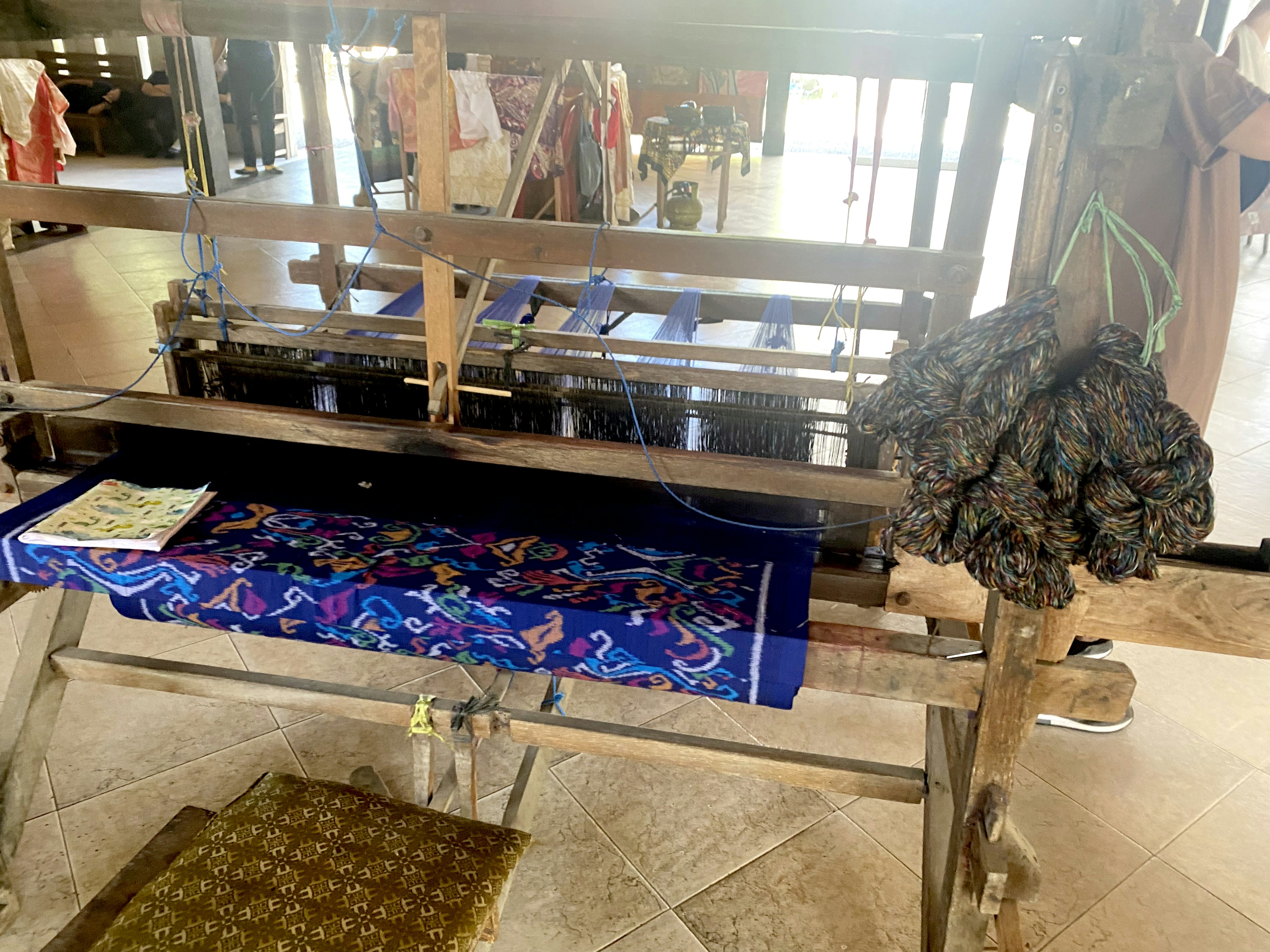 Traditional loom with intricate blue fabric in a workshop