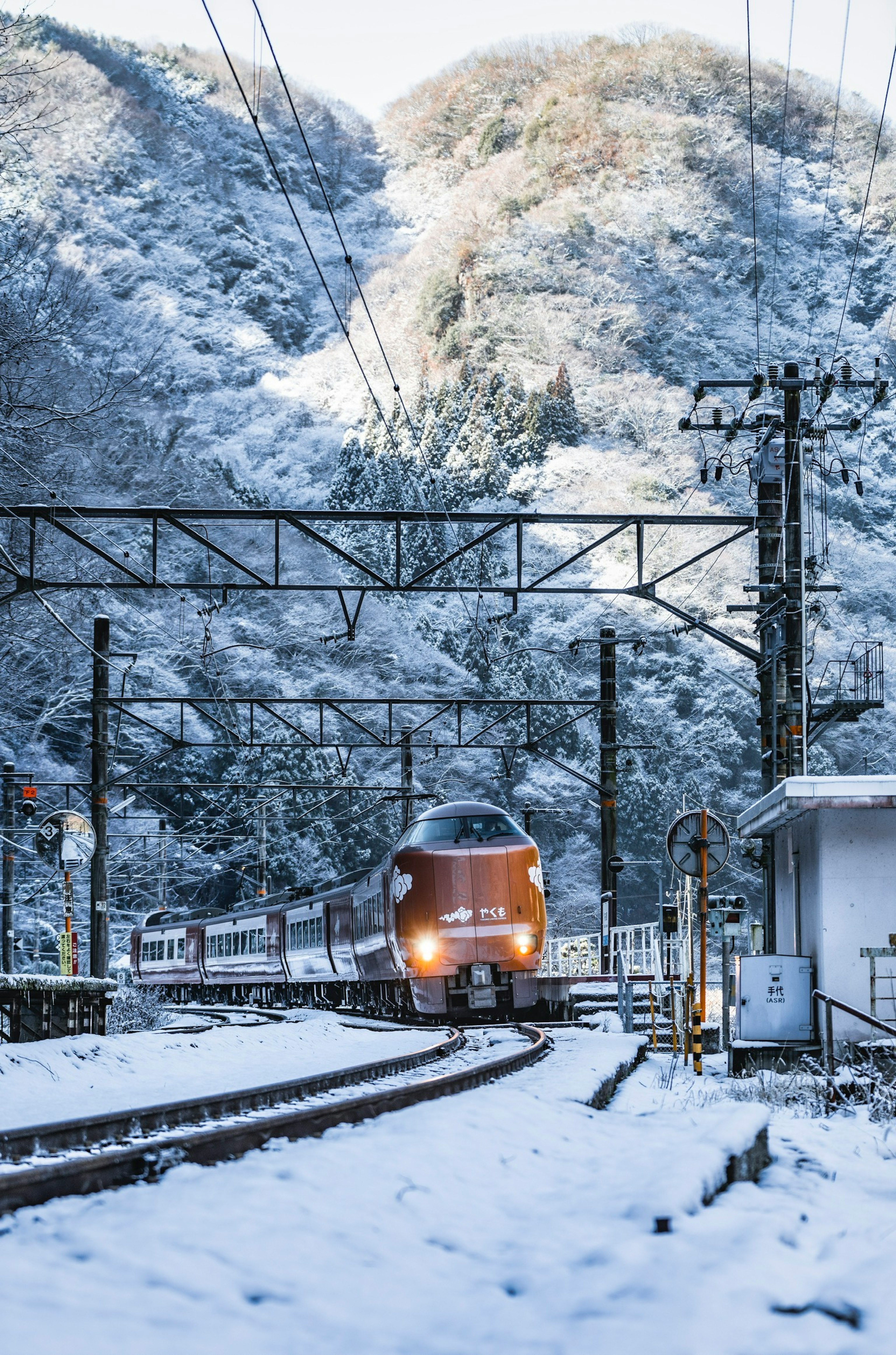 Red train traveling through snow-covered mountains