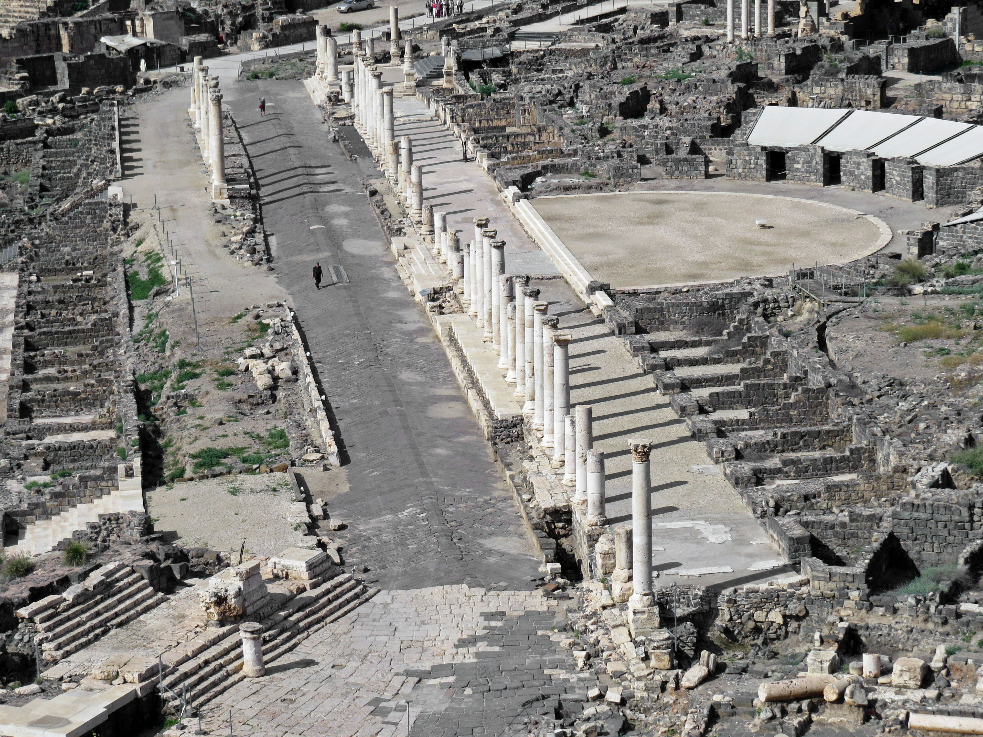 Vue des ruines anciennes avec une route et un théâtre circulaire avec des colonnes brisées et des pierres