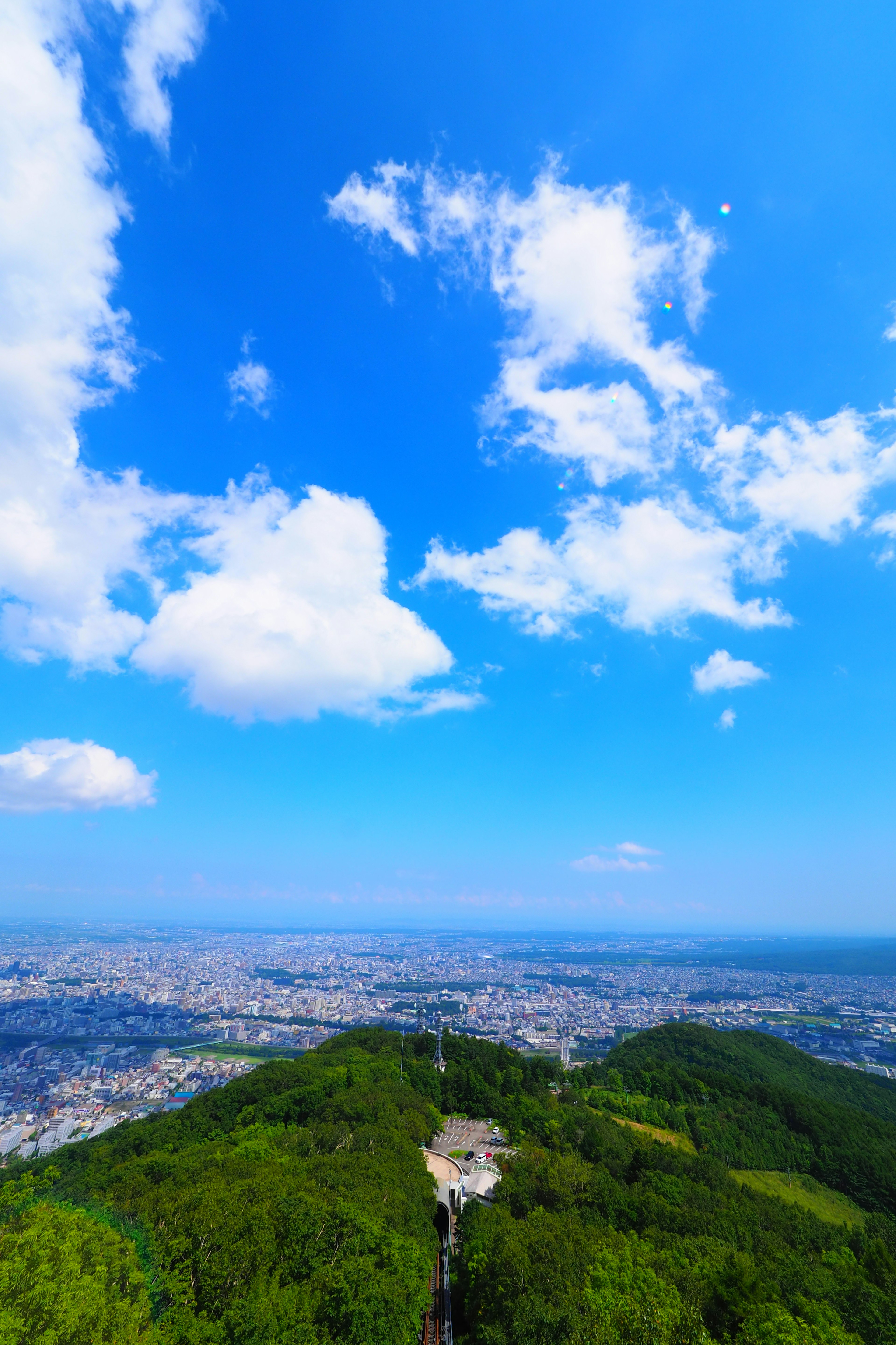 青空と白い雲が広がる山の頂上からの眺め