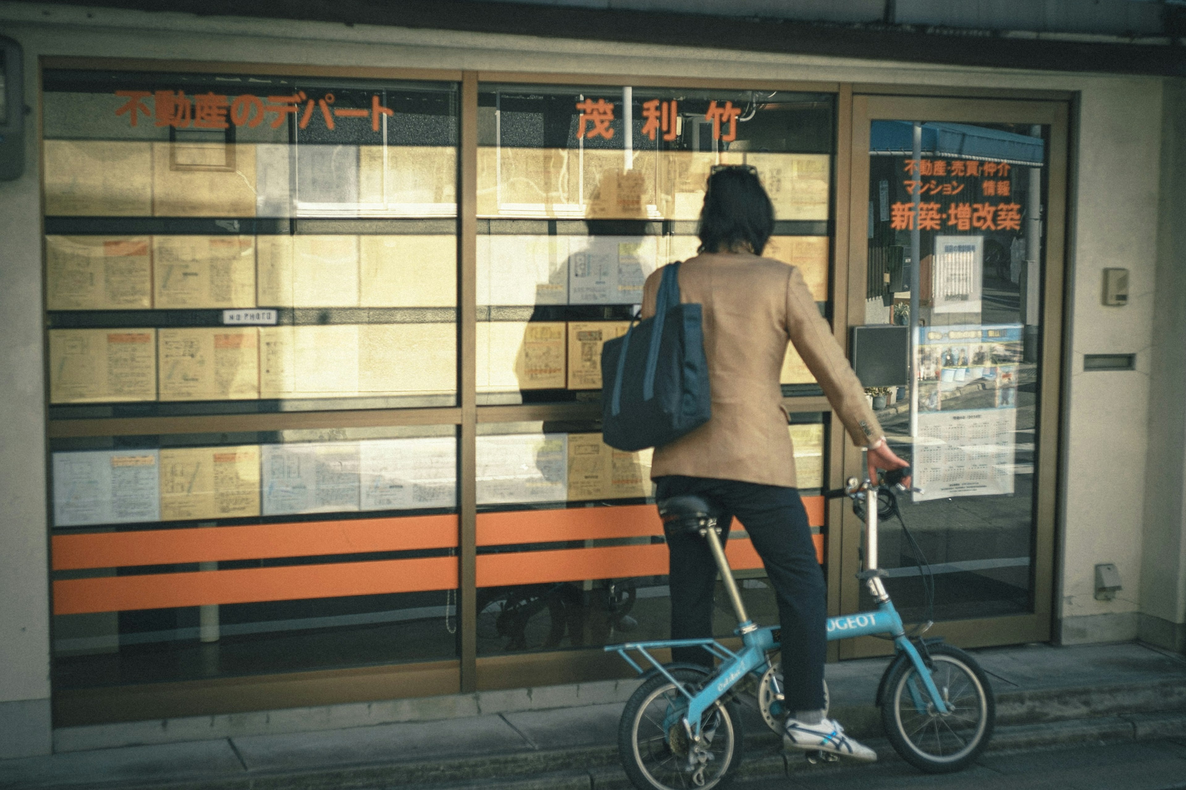 Una mujer en bicicleta se encuentra frente a una ventana con acentos naranjas