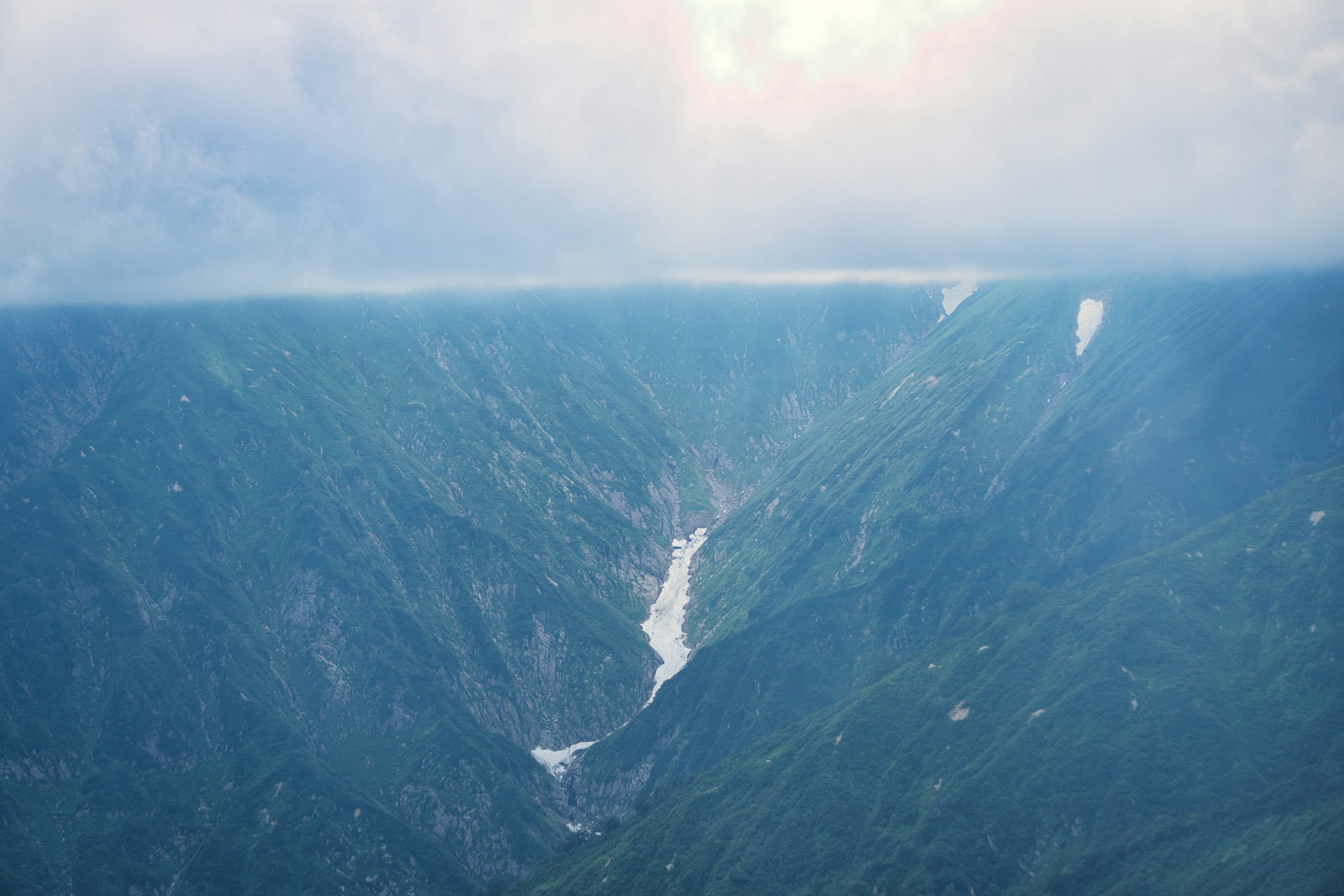 蓝色山脉和峡谷风景 多云的天空和融化的雪流动的水