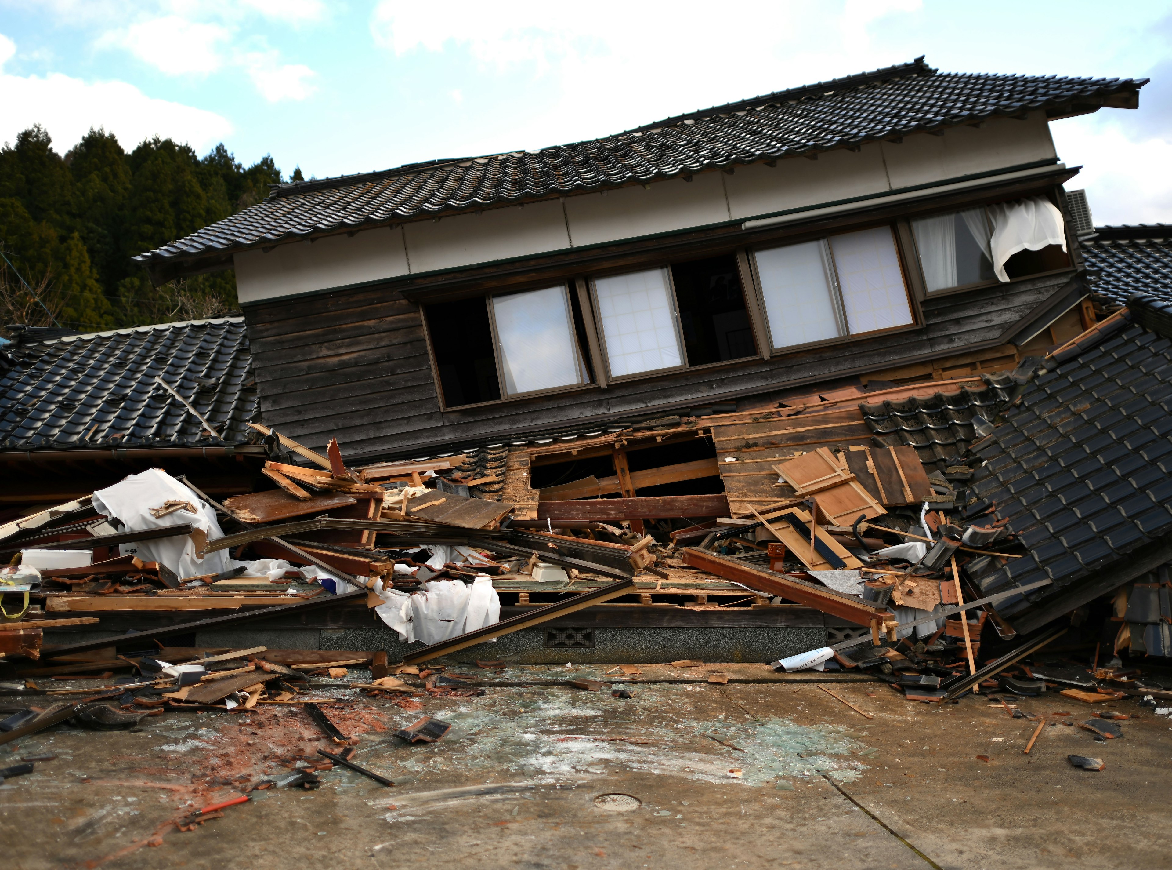 Casa japonesa colapsada con escombros y destrucción circundante