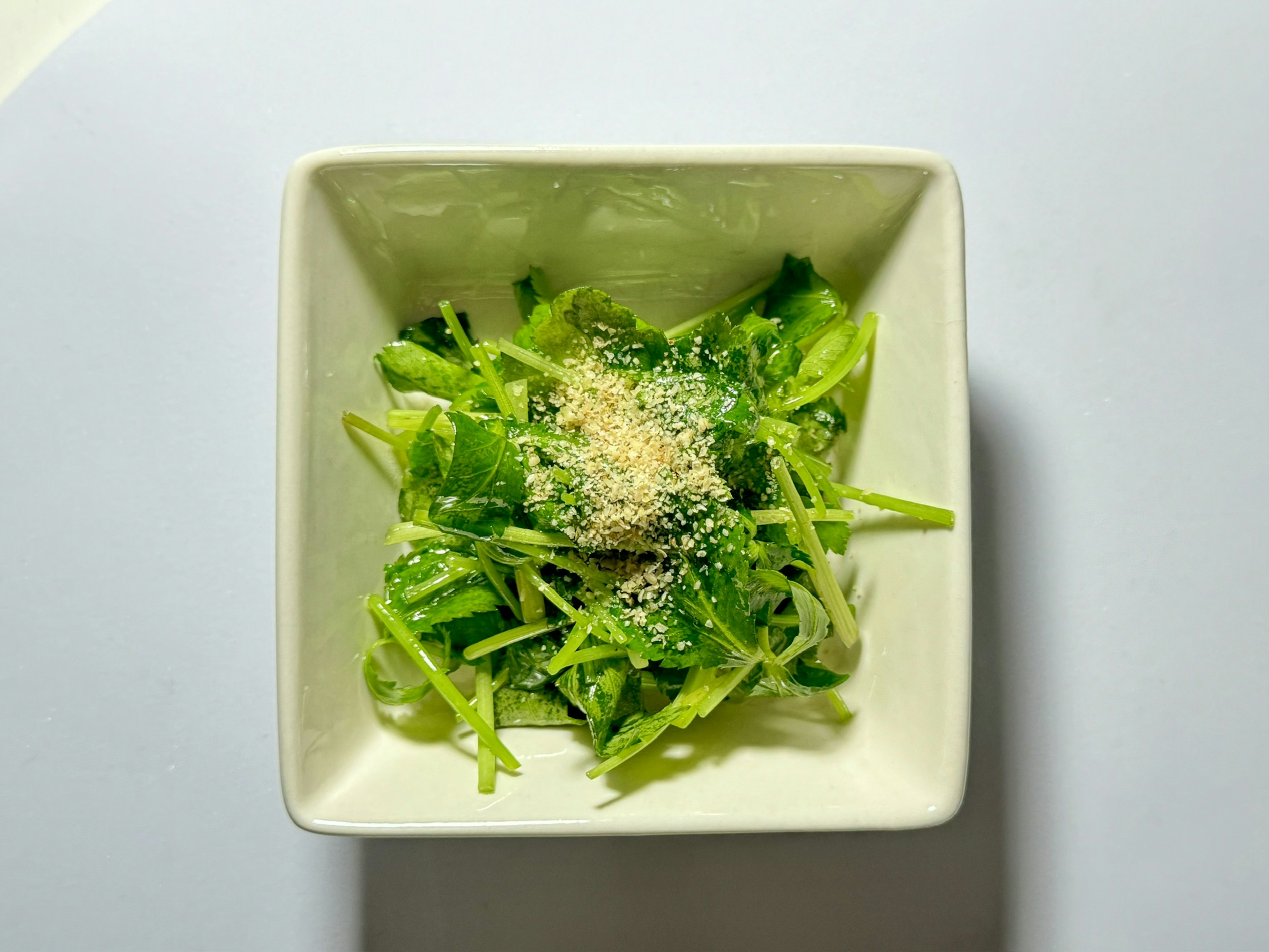 Salade verte fraîche garnie de graines de sésame dans un plat blanc