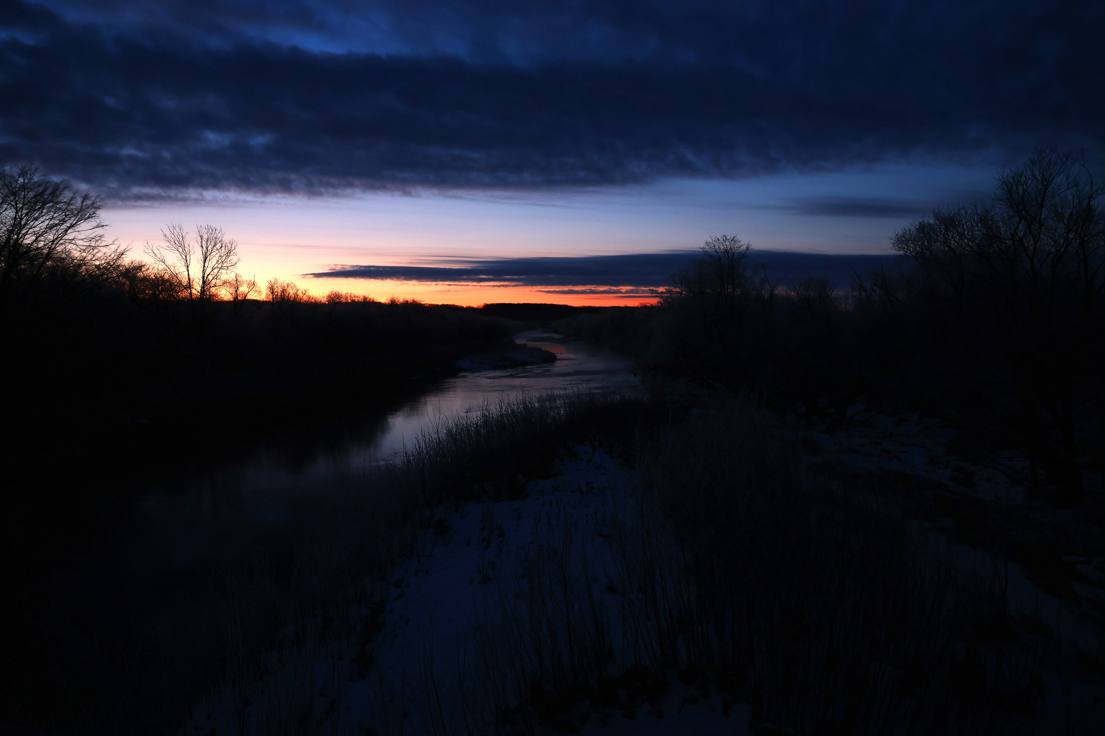 Una escena serena de un río con un cielo oscuro y colores vibrantes del atardecer