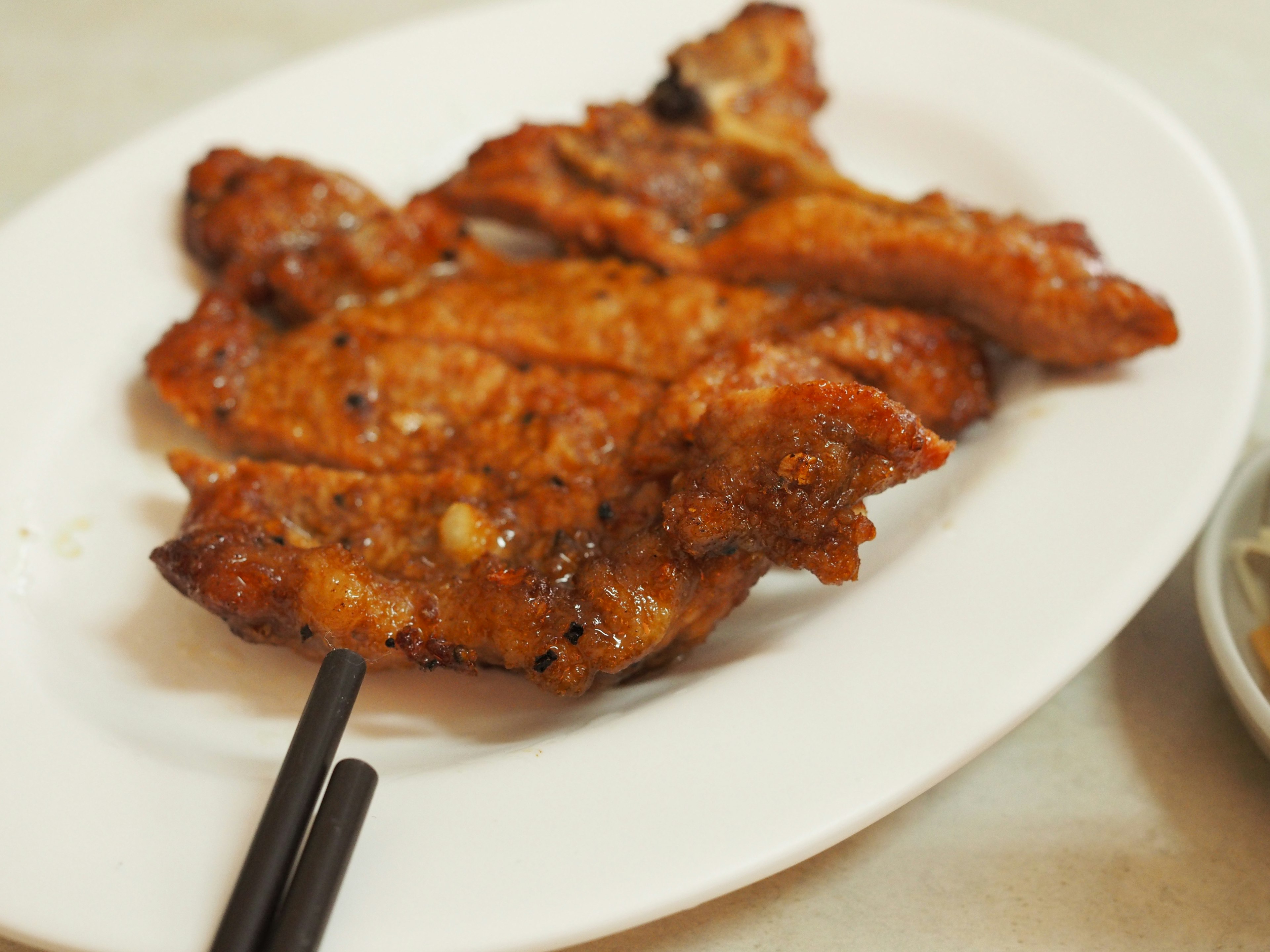 Pollo a la parrilla en un plato blanco con palillos